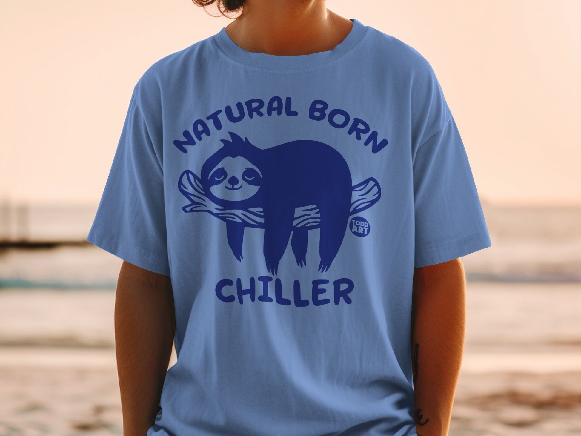Blue t-shirt with "Natural Born Chiller" text and a sloth on a branch.