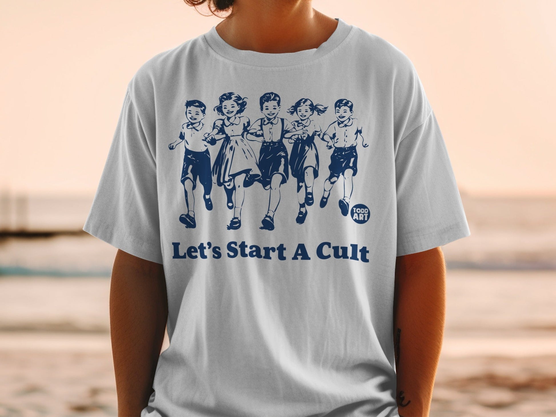 White t-shirt with blue graphic of running children and text "Let's Start A Cult".