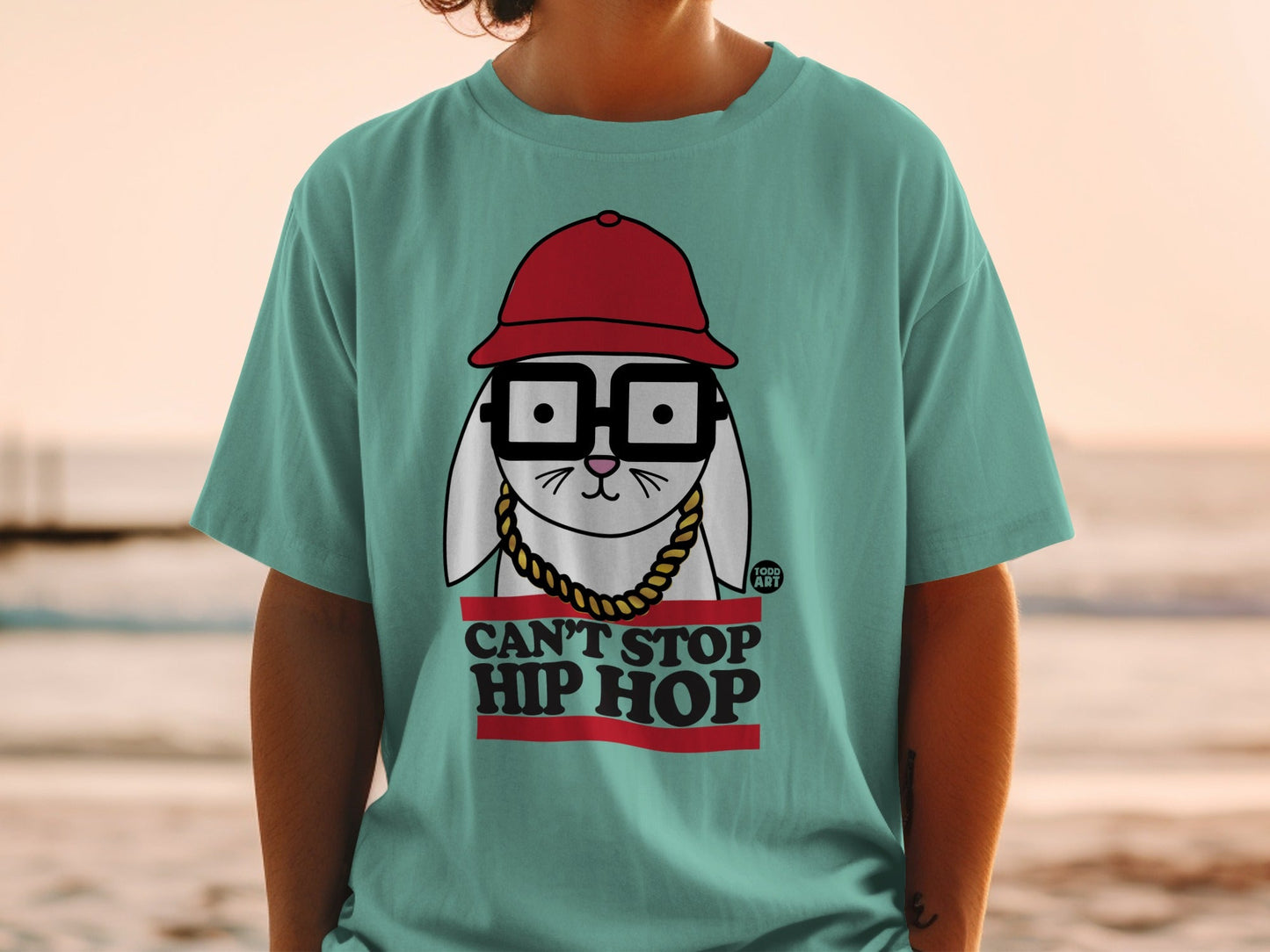 White rabbit graphic wearing glasses and a red hat on a teal t-shirt.