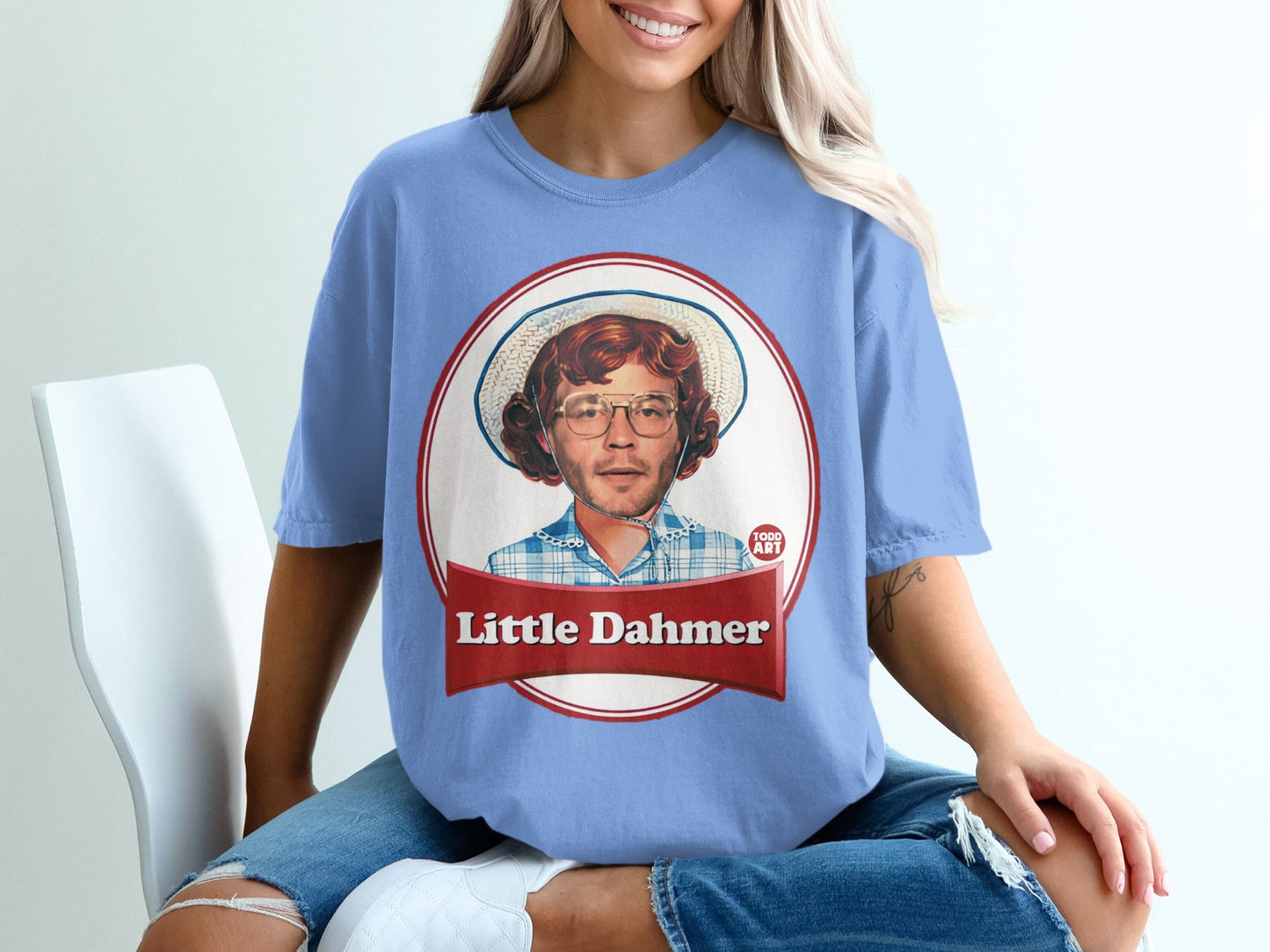 Blue t-shirt with Little Dahmer graphic on a person wearing ripped jeans.
