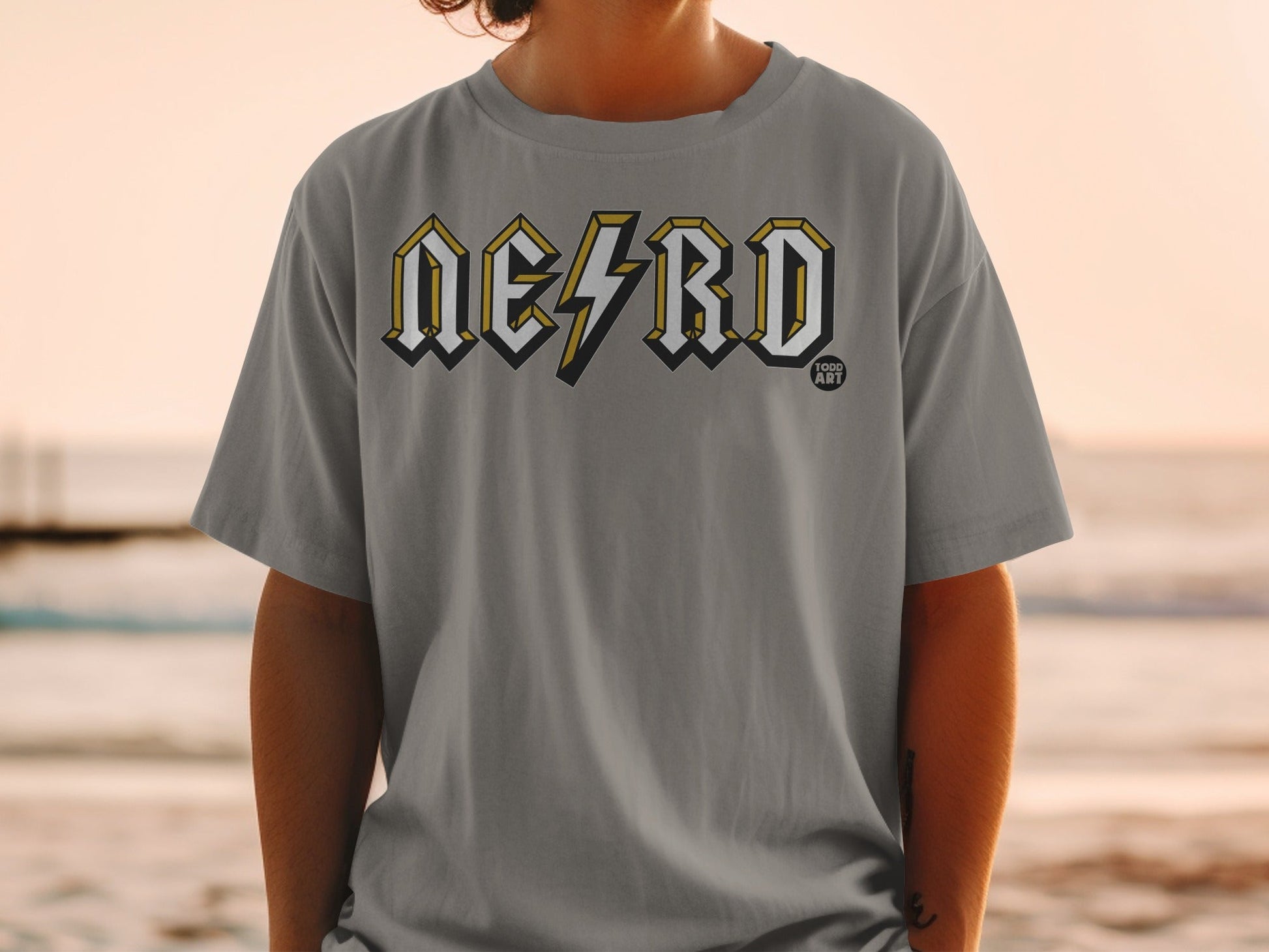 Grey t-shirt with "NERD" logo in yellow and black, person wearing it.
