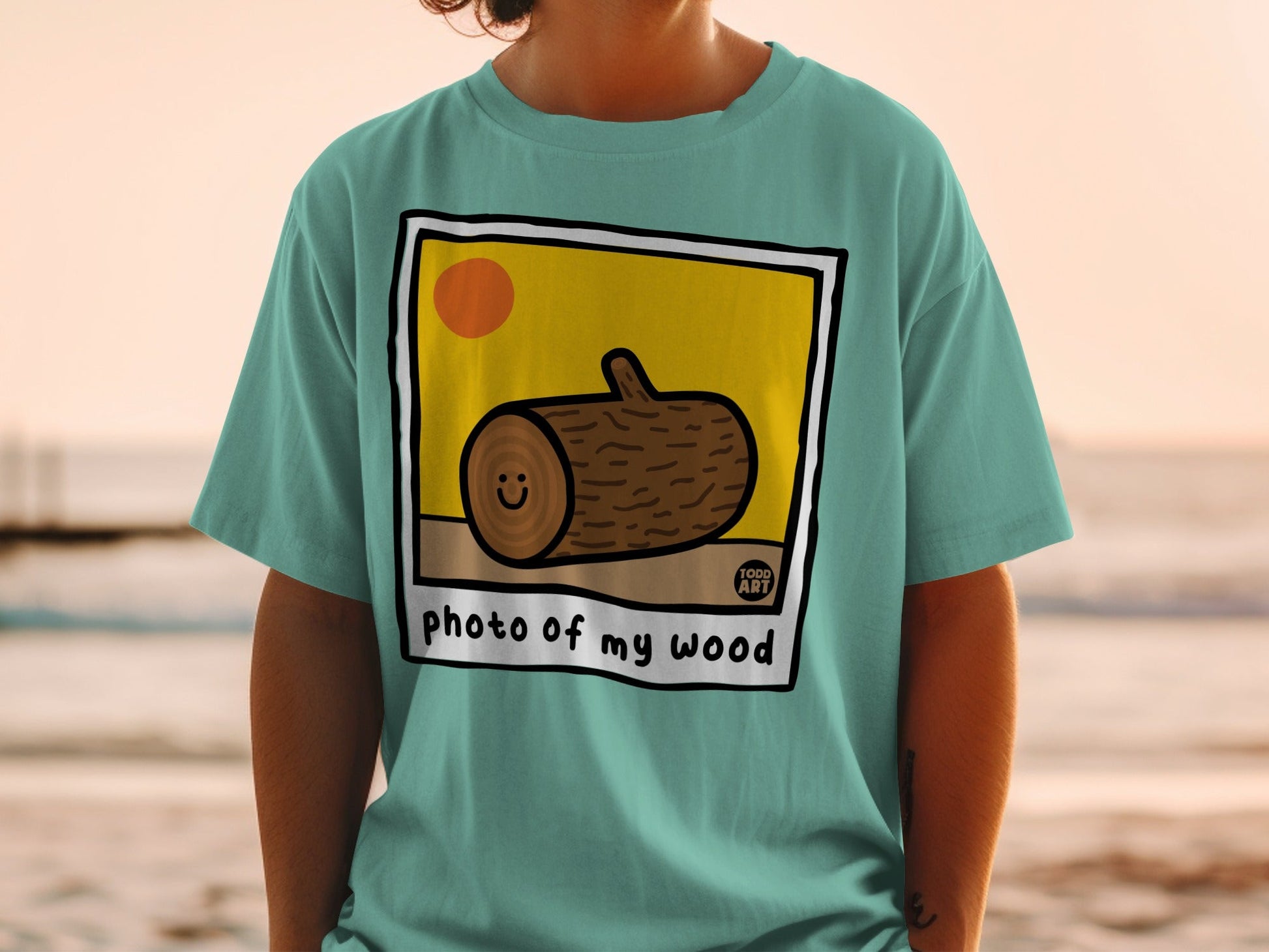Teal t-shirt with a cartoon wood log smiling inside a framed photo.