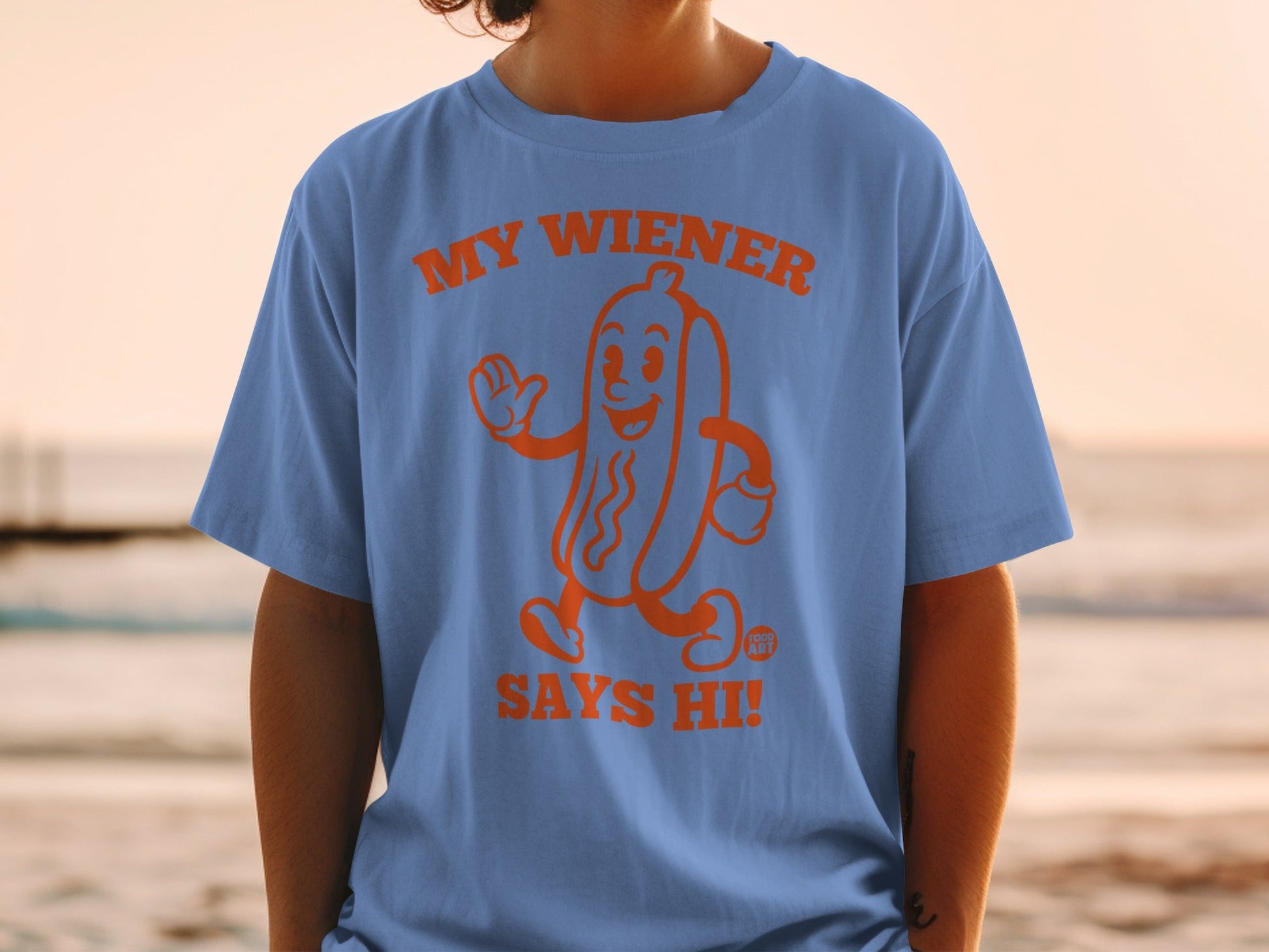 Blue t-shirt with orange cartoon hot dog saying "MY WIENER SAYS HI!".
