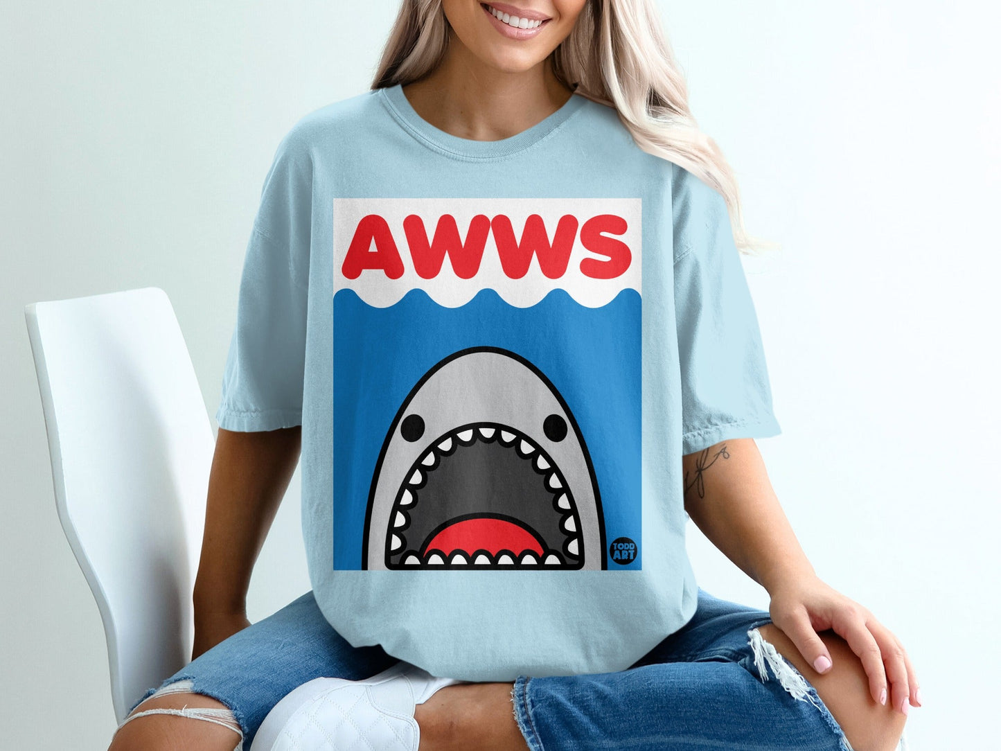 Light blue t-shirt with cartoon shark and "AWWS" text on waves.