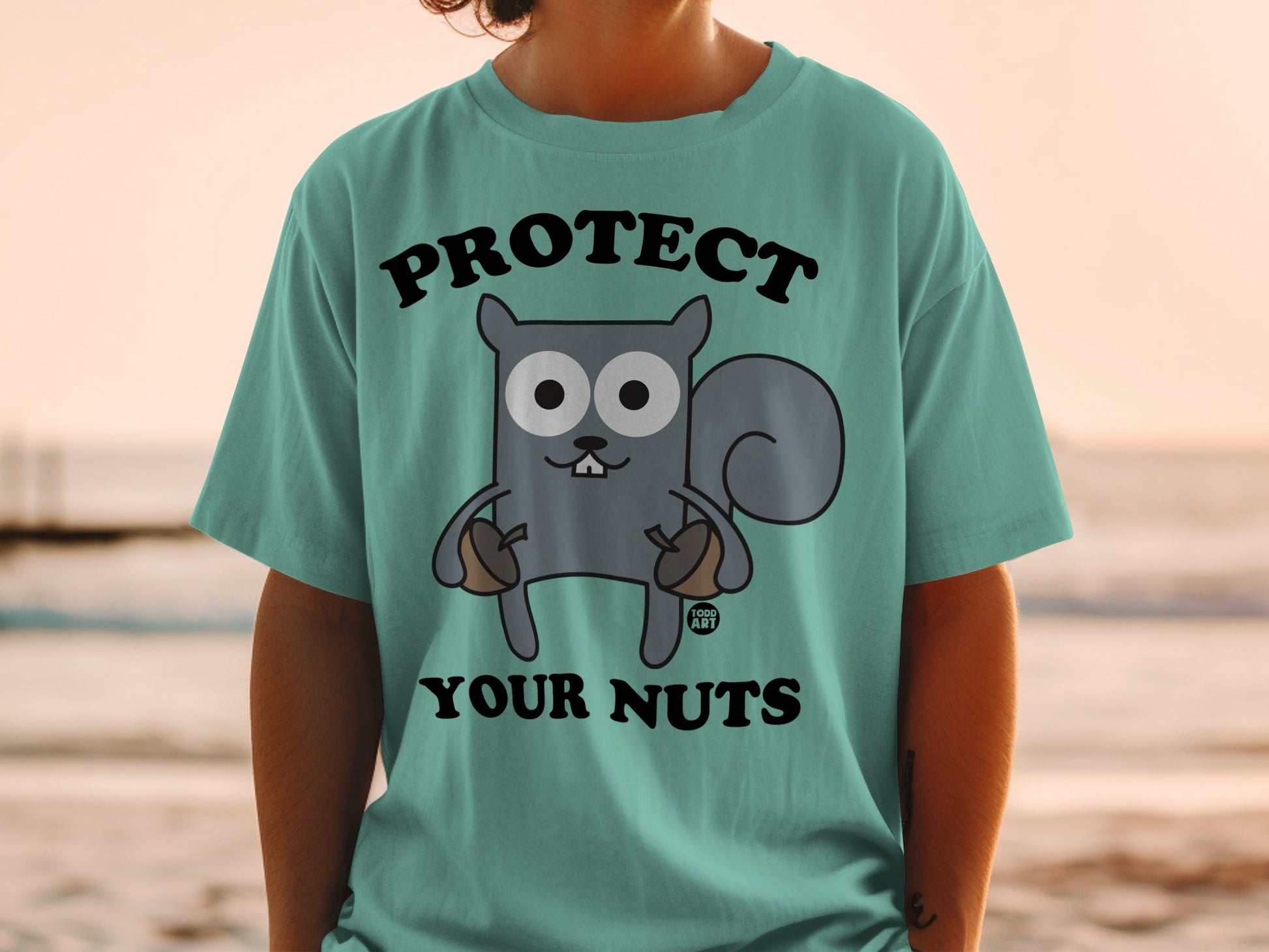 Teal t-shirt with cartoon squirrel holding acorns, "Protect Your Nuts" text.