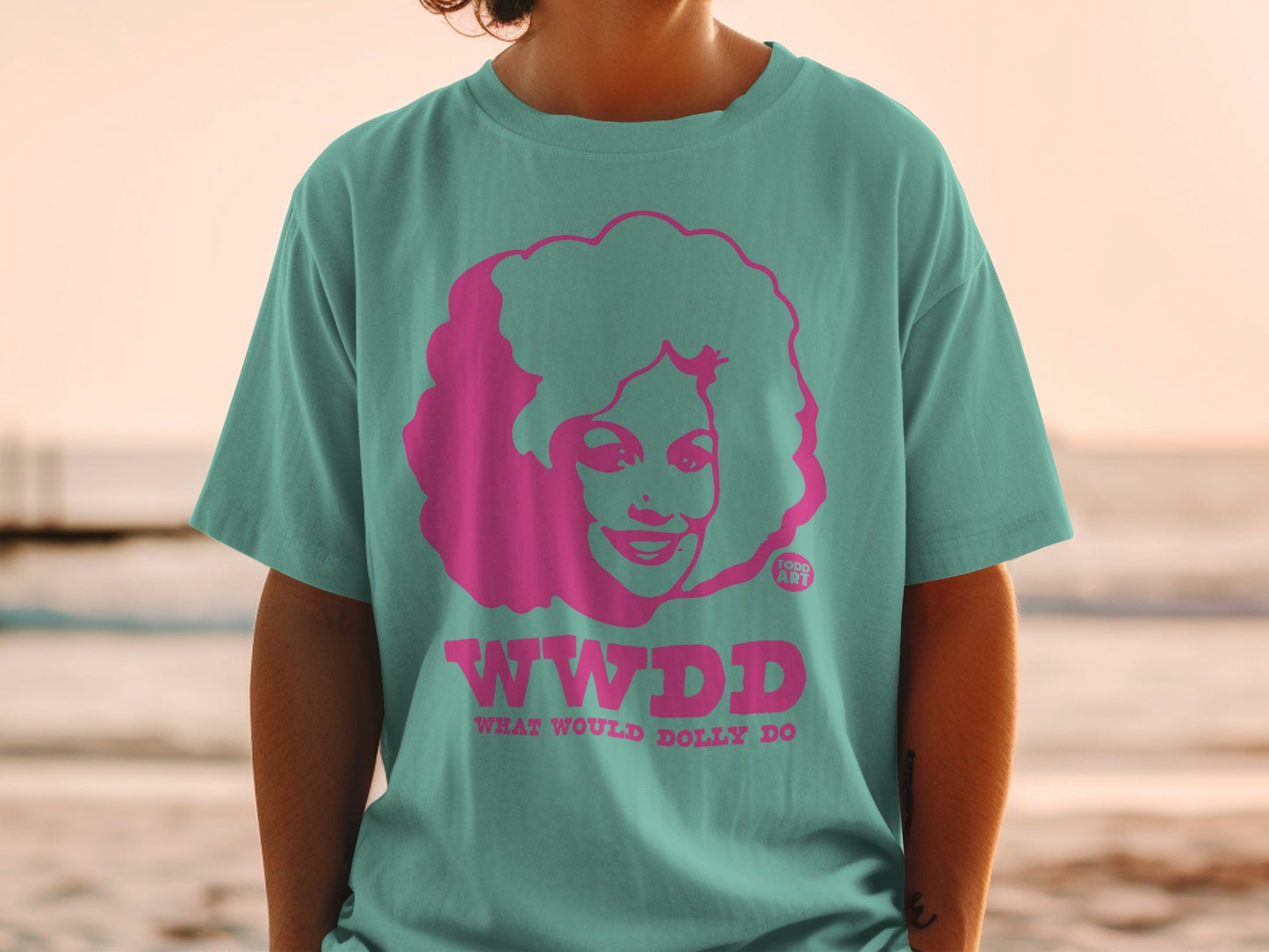 Teal t-shirt with pink "WWDD WHAT WOULD DOLLY DO" text and Dolly Parton graphic.