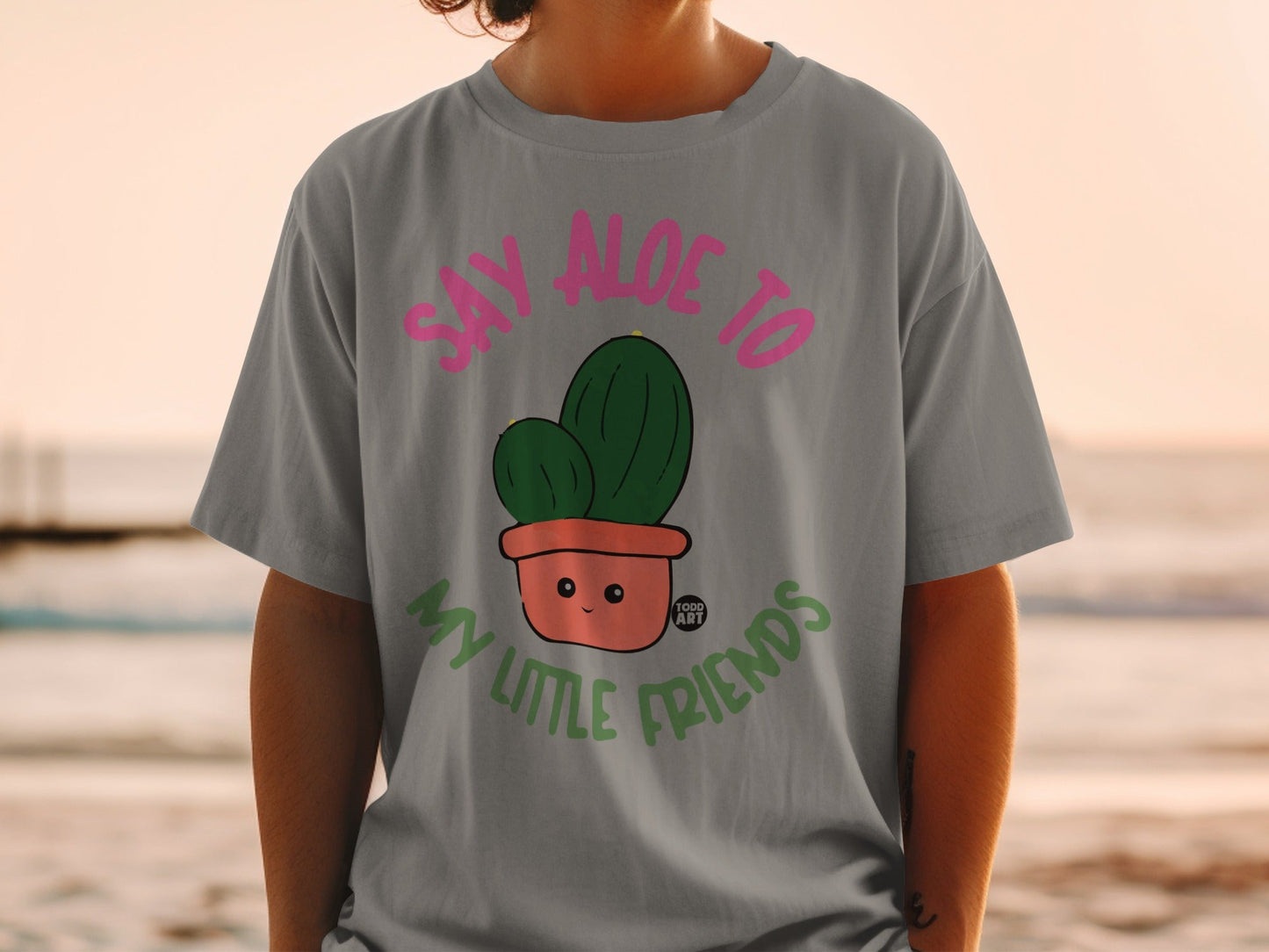 T-shirt with a potted cactus illustration and text "Say aloe to my little friends".