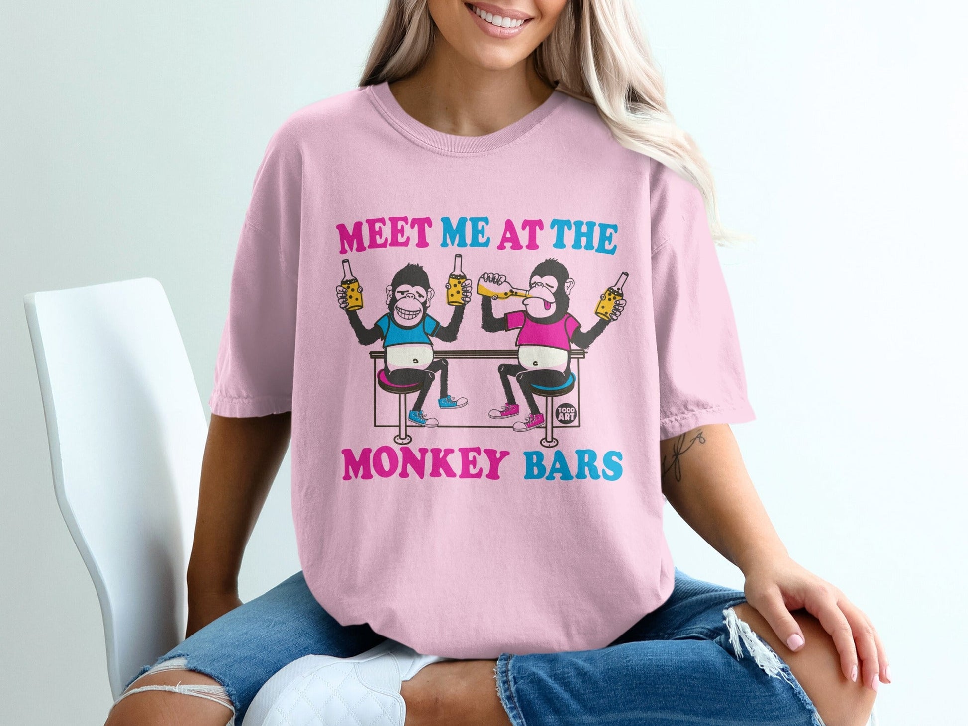 Pink t-shirt with illustration of two monkeys drinking at a bar.