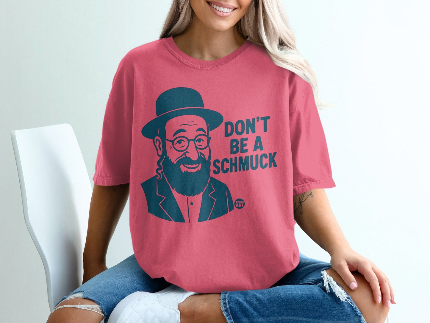 Woman wearing a pink t-shirt with "DON'T BE A SCHMUCK" and a cartoon man.