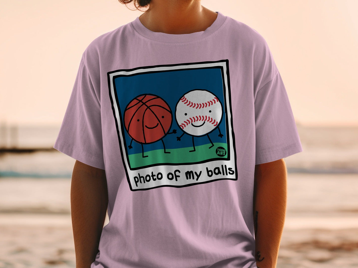 Cartoon basketball and baseball characters holding hands on a pink t-shirt.