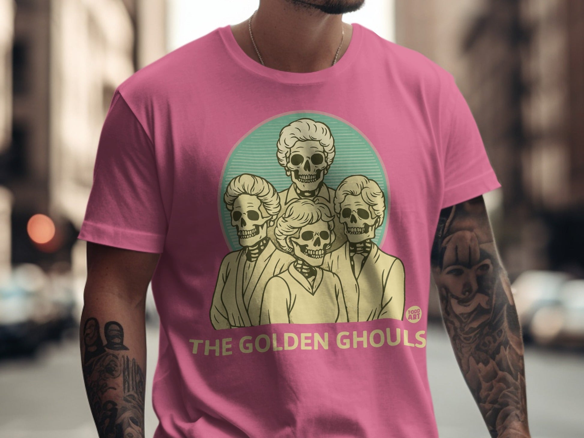 Pink t-shirt featuring "The Golden Ghouls" logo with four skeleton figures.