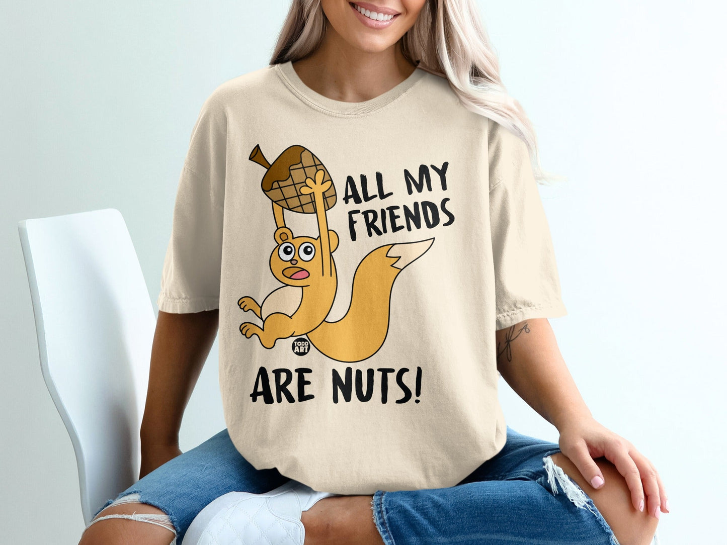 Cream t-shirt with a cartoon squirrel holding an acorn, reading "All my friends are nuts!".