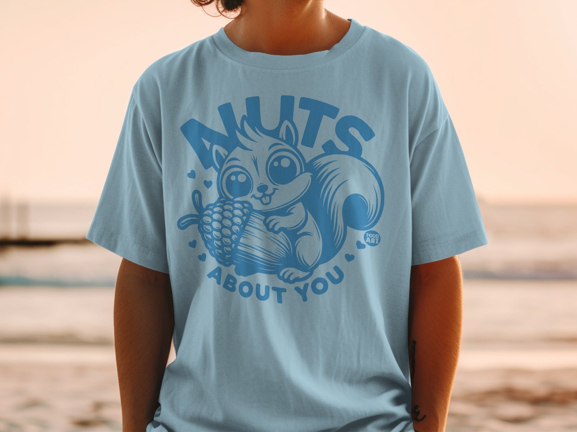 Light blue t-shirt with a cartoon squirrel holding a pinecone and the text "nuts about you".