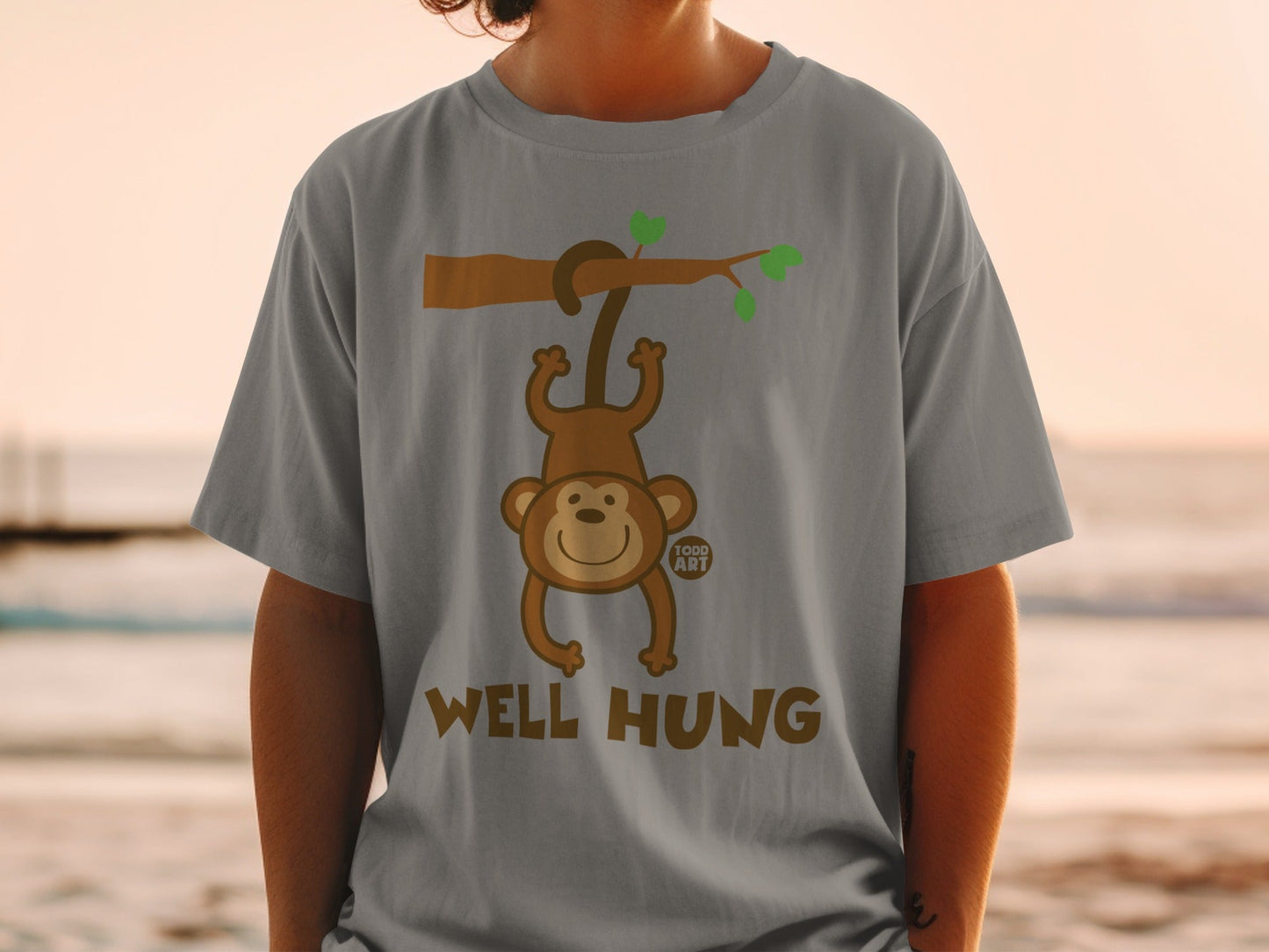 Grey t-shirt with a cartoon monkey hanging from a branch, text reads "Well Hung".