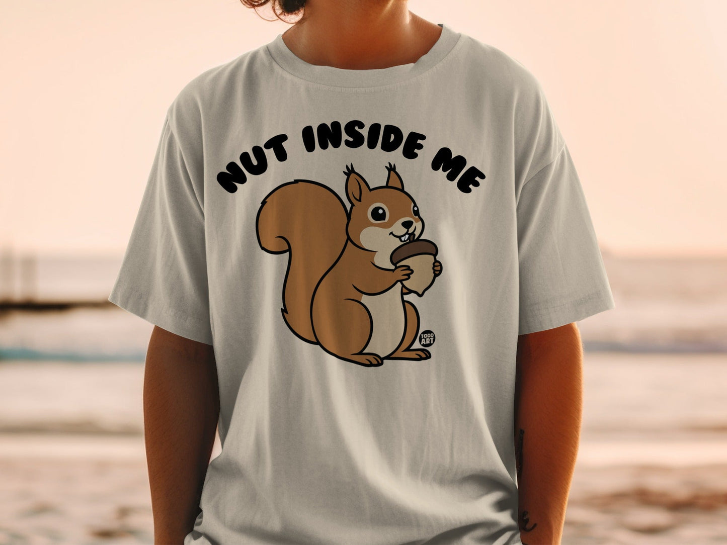 T-shirt with a cartoon squirrel holding an acorn, text "NUT INSIDE ME".