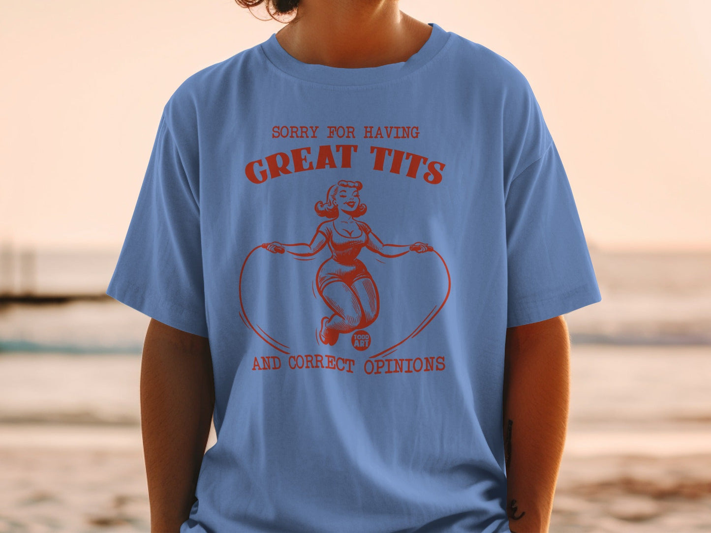 Blue t-shirt with red graphic of a woman jumping rope and text "SORRY FOR HAVING GREAT TITS AND CORRECT OPINIONS".