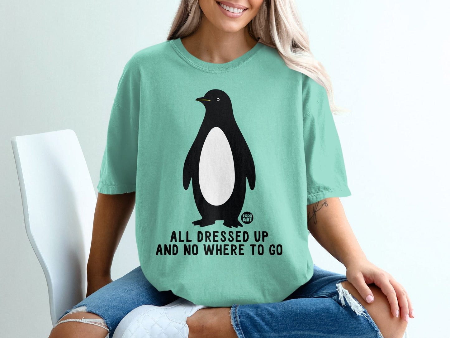 Teal t-shirt with penguin graphic and "ALL DRESSED UP AND NO WHERE TO GO" text.