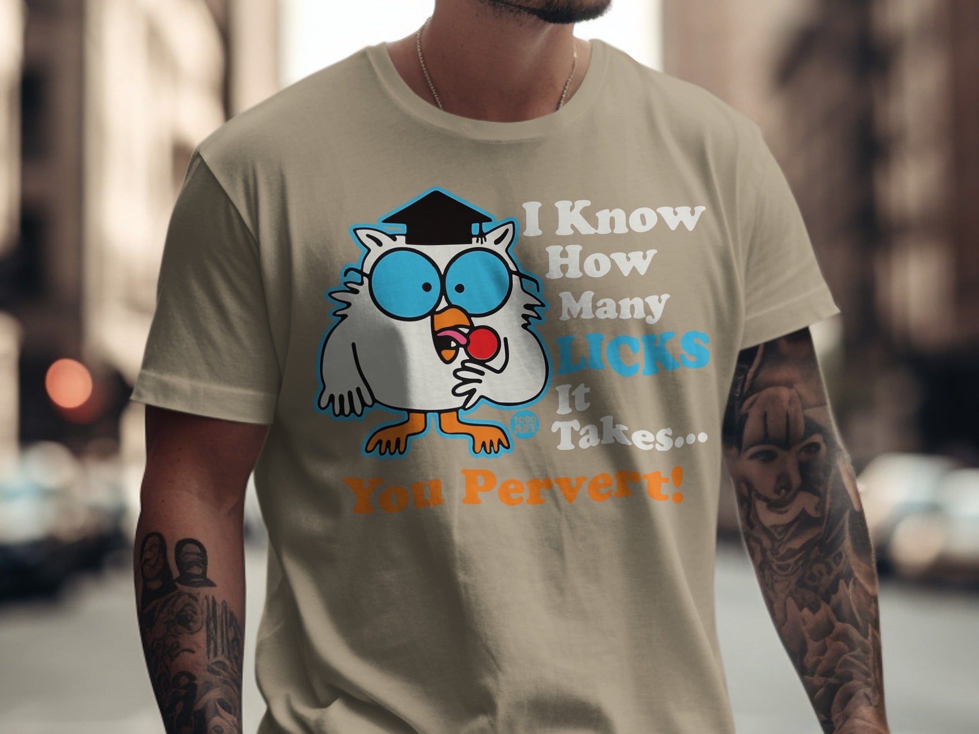 Owl wearing graduation cap and glasses holding lollipop on tan t-shirt.