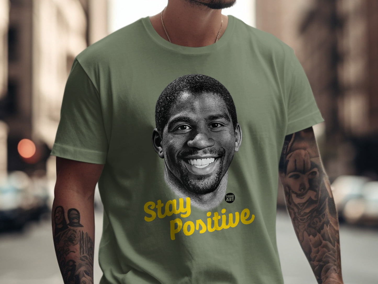 Magic Johnson portrait with "Stay Positive" text on a green t-shirt.