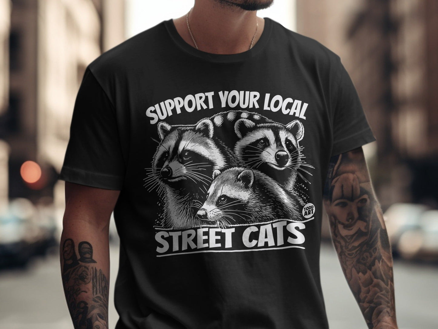T-shirt with raccoons and text "Support Your Local Street Cats".