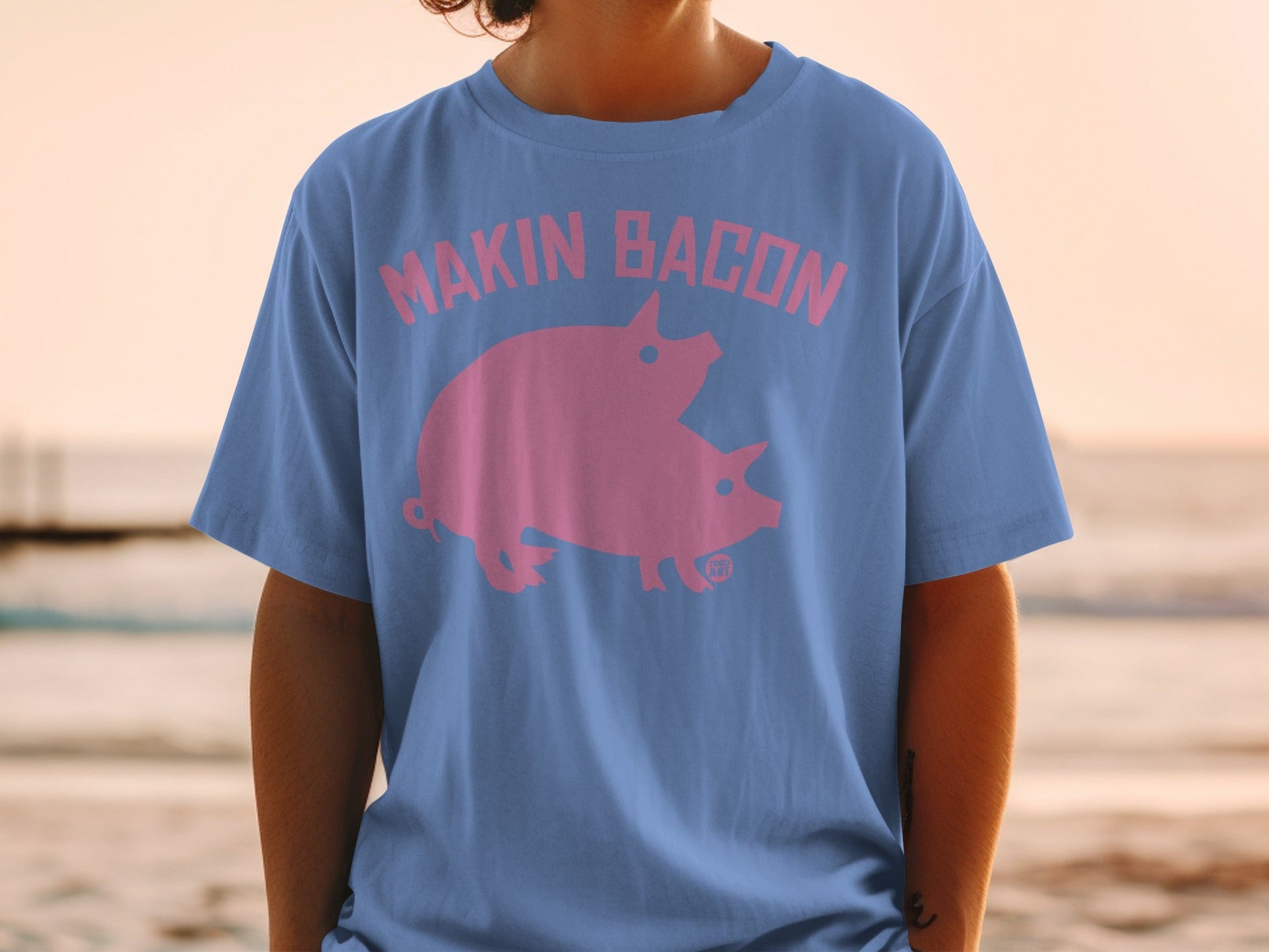 Blue t-shirt with pink "Makin Bacon" text and two pigs graphic.