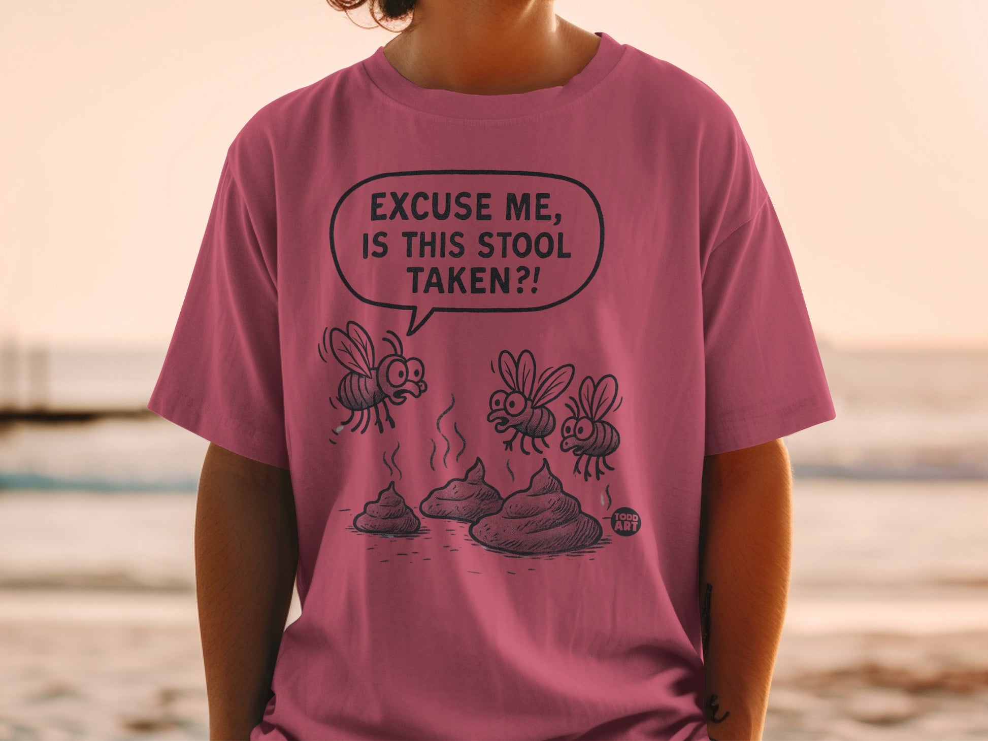 Man wearing a pink t-shirt with cartoon flies and poop, text "Excuse me, is this stool taken?!"