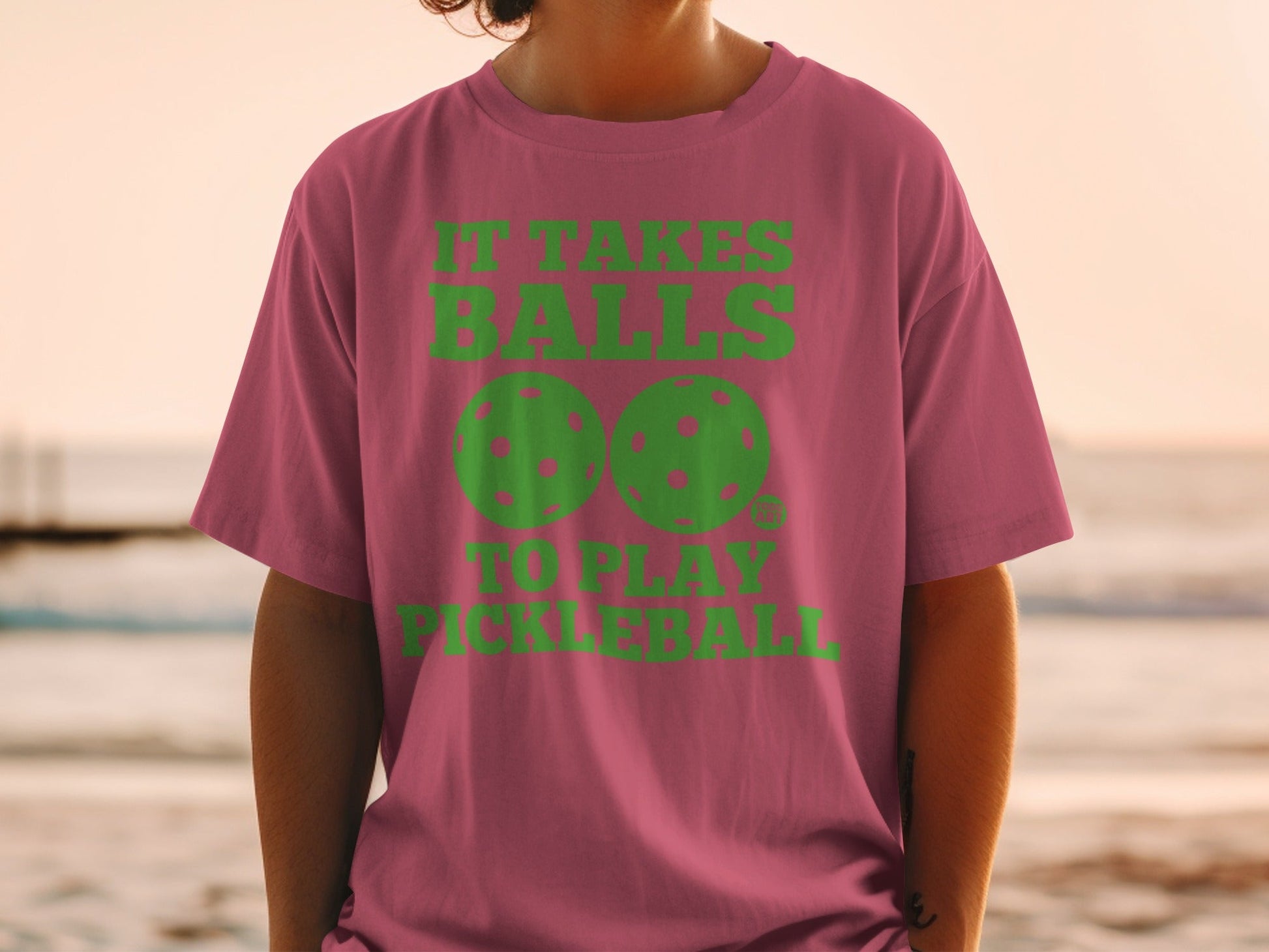 Pink t-shirt with green text "It Takes Balls To Play Pickleball" and pickleball graphics.