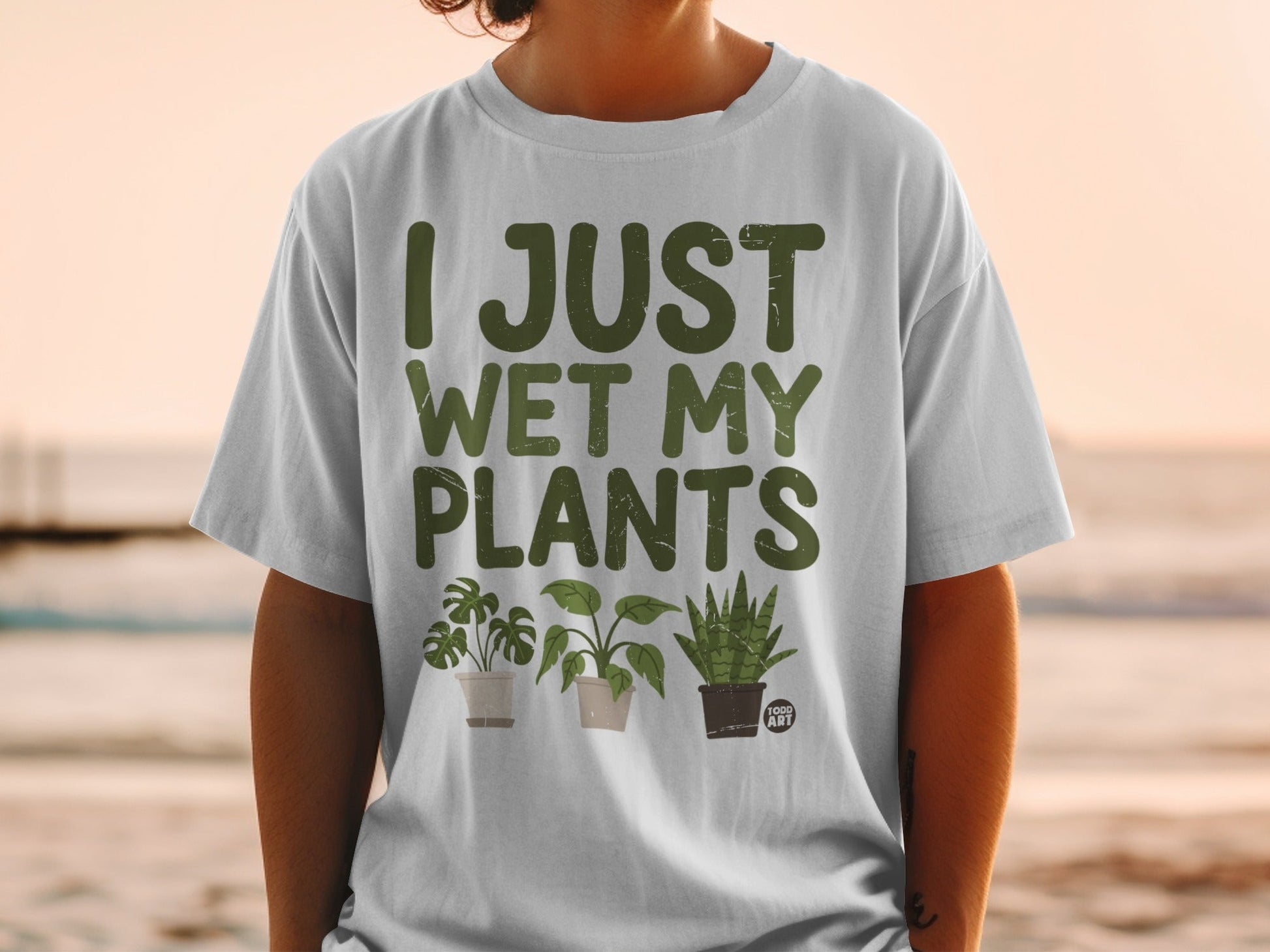 T-shirt with "I JUST WET MY PLANTS" text and three potted houseplants.