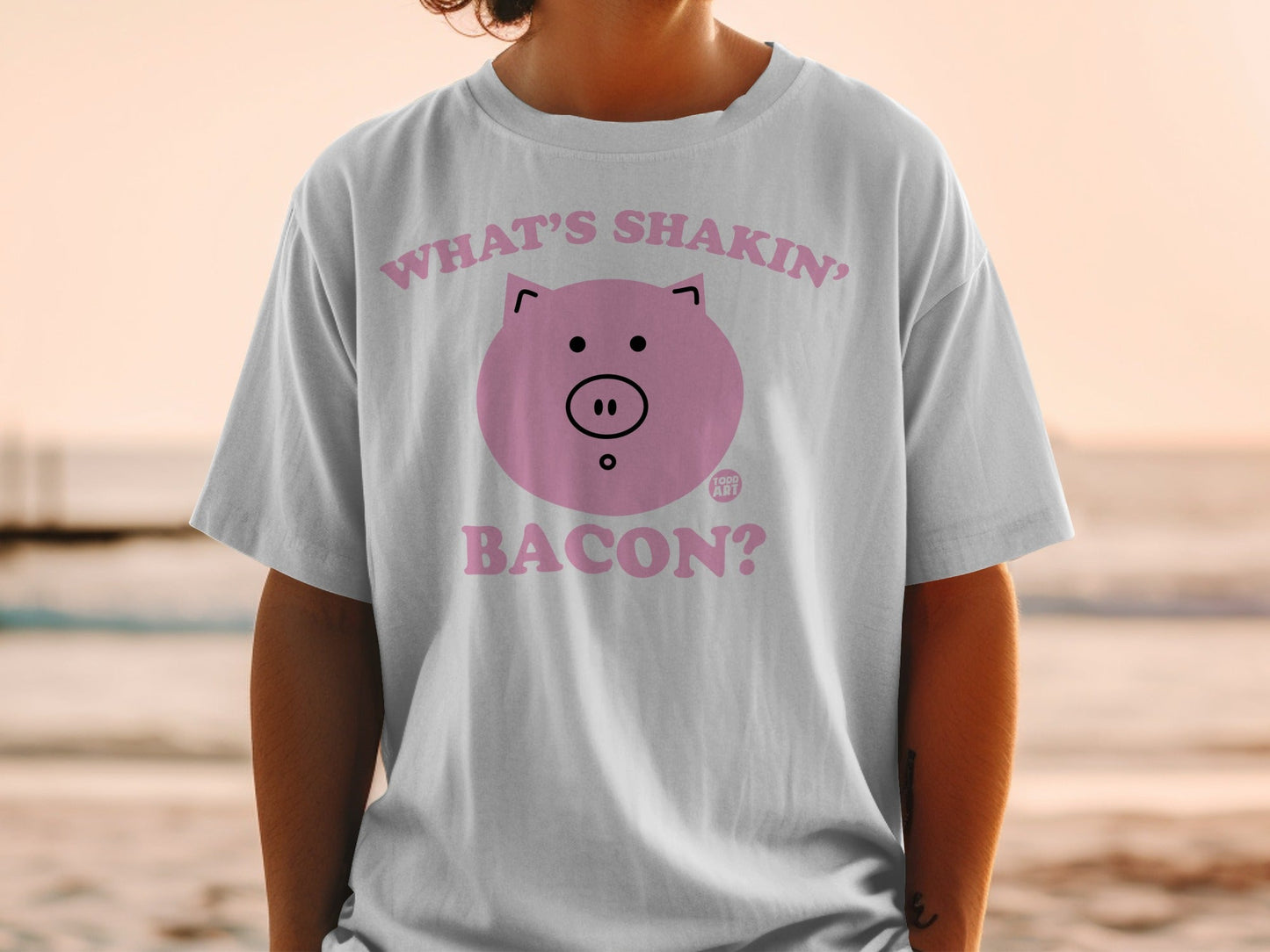 White t-shirt with pink pig graphic and "What's shakin'? Bacon?" text.