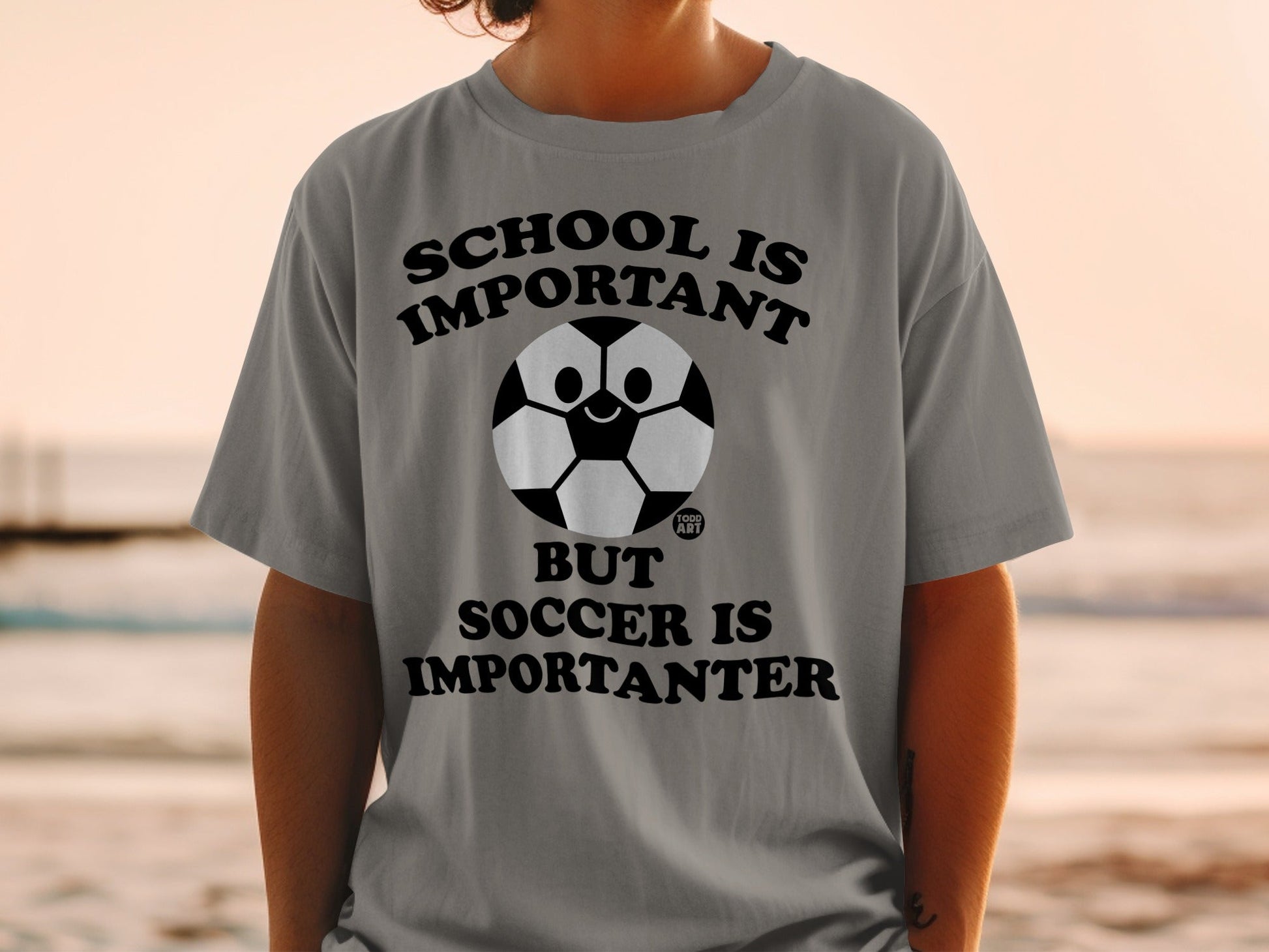 Gray t-shirt with "SCHOOL IS IMPORTANT BUT SOCCER IS IMPORTANTER" and a soccer ball face.