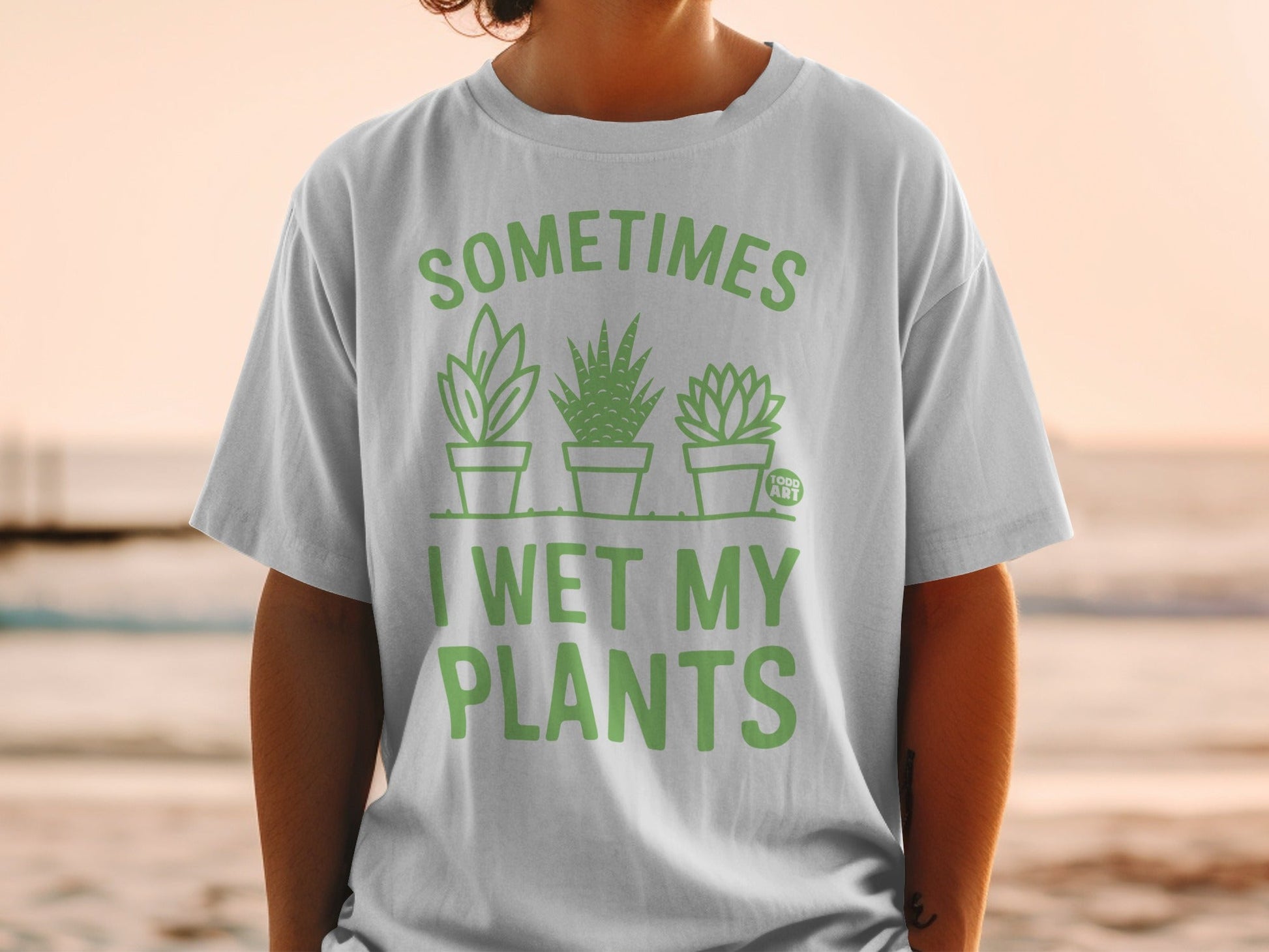 Green t-shirt with text "SOMETIMES I WET MY PLANTS" and plant illustrations.