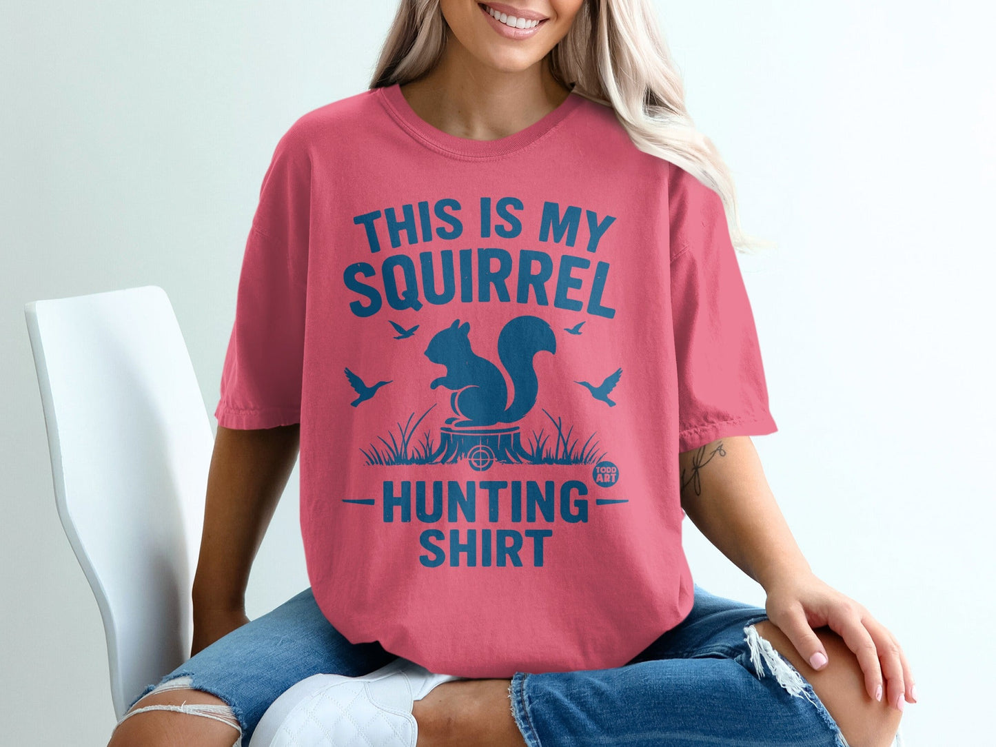 Coral t-shirt with blue graphic: "This is my squirrel hunting shirt" and a squirrel on a stump.