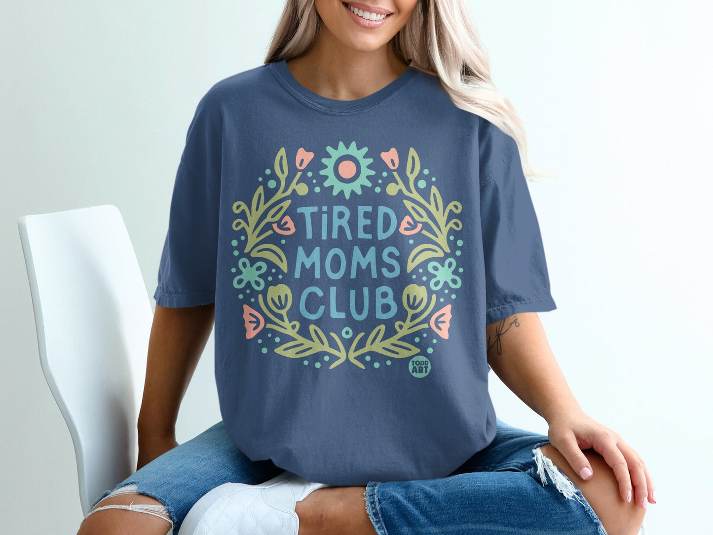 Navy t-shirt with "Tired Moms Club" in a floral wreath design.