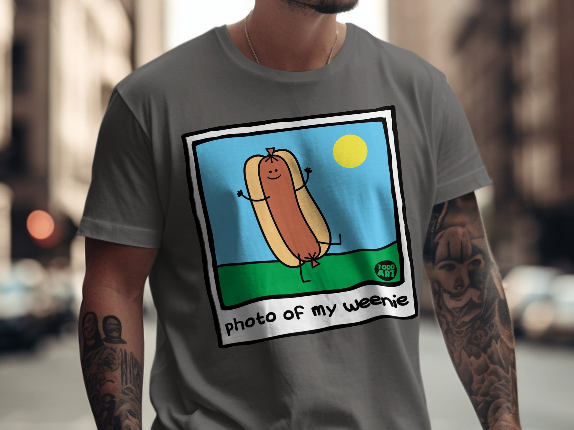T-shirt featuring a cartoon hot dog with arms and legs, captioned "photo of my weenie".