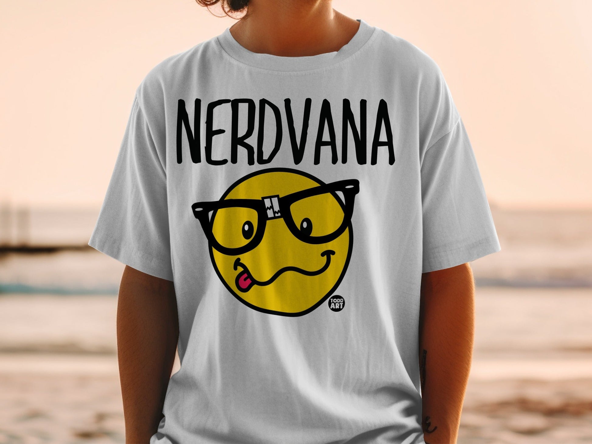 White t-shirt with "NERDVANA" text and a smiley face with glasses and tongue out.