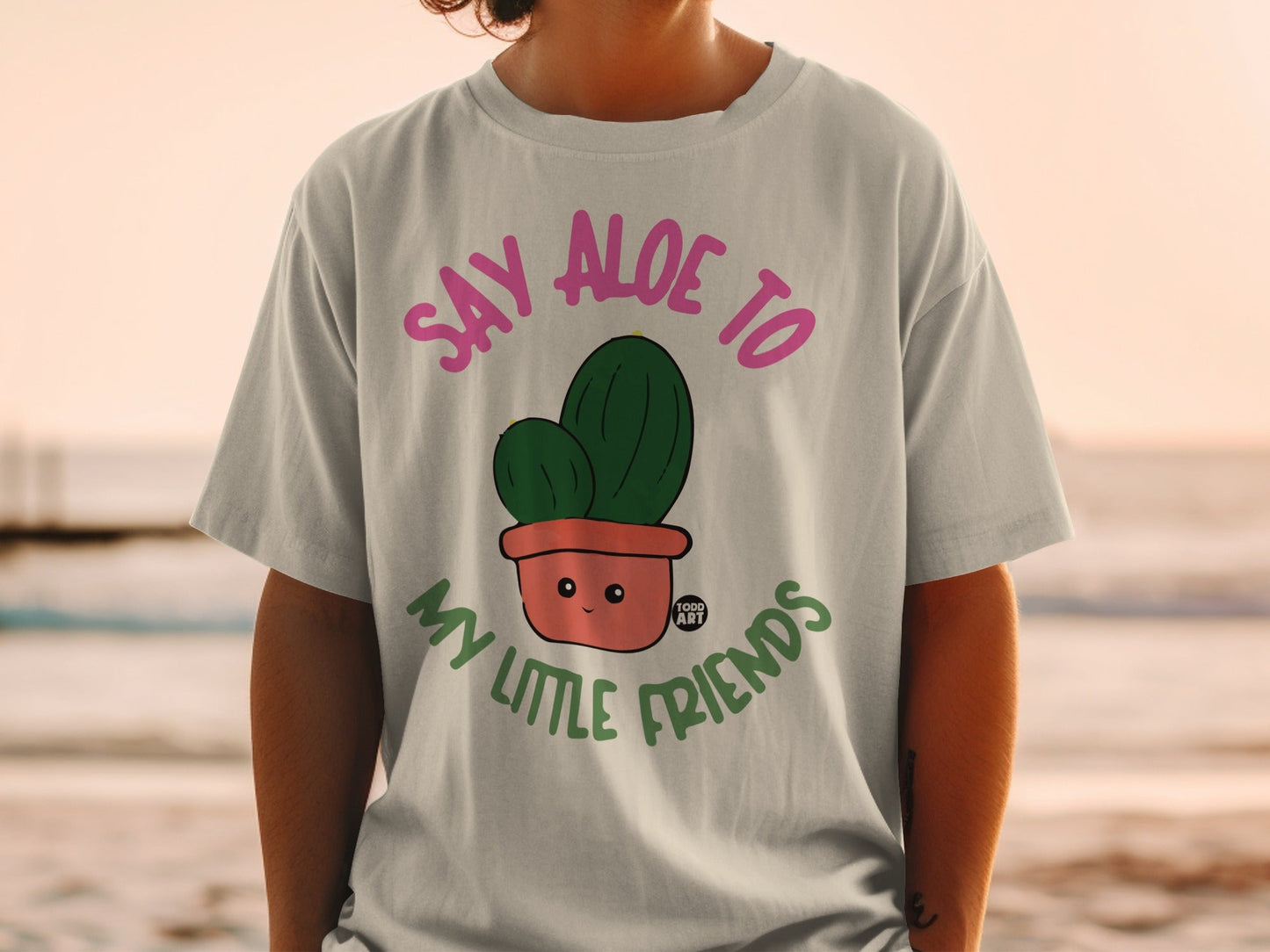 T-shirt with cartoon cactus in pot that says "Say aloe to my little friends."