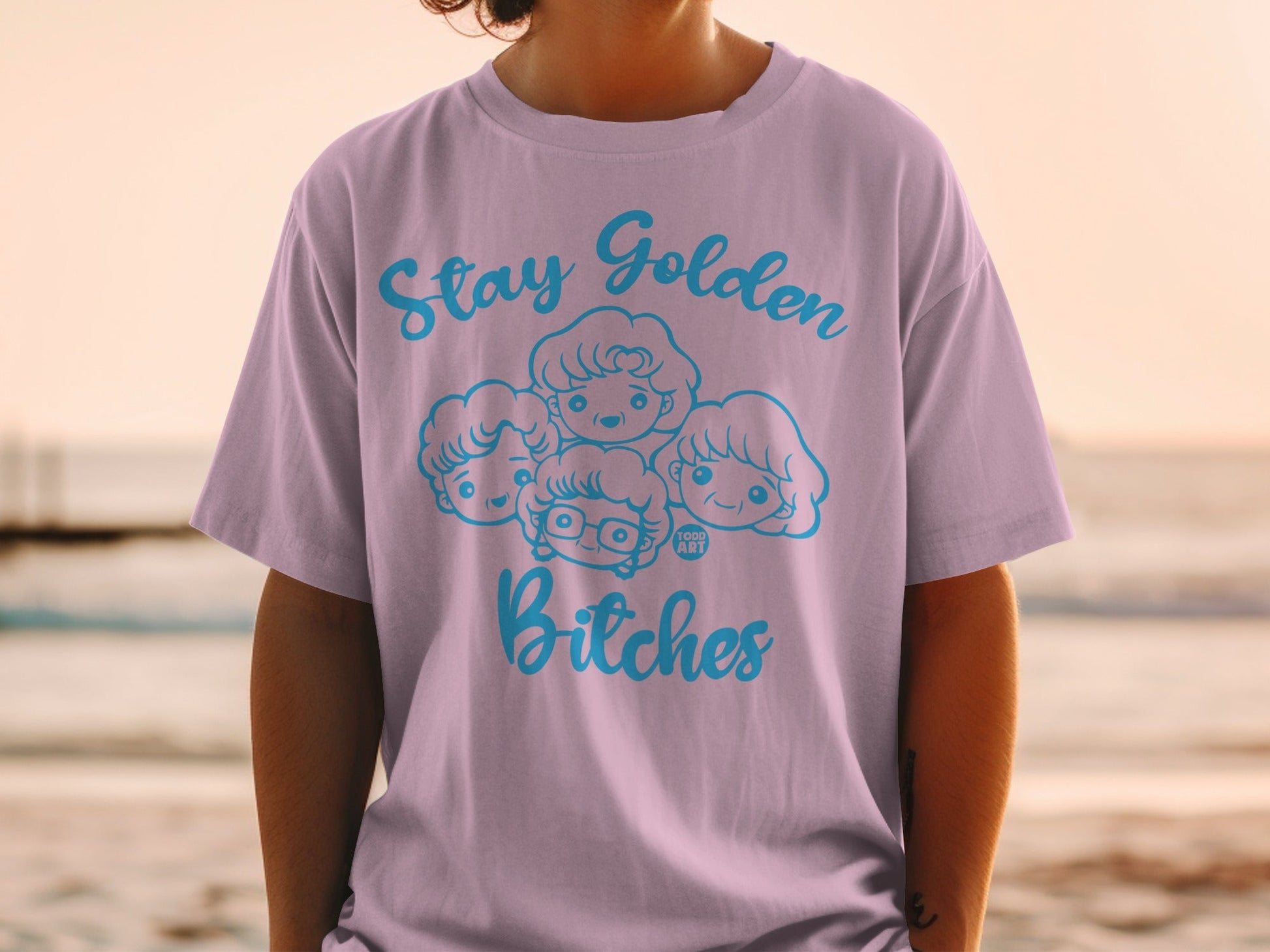 Light purple t-shirt with "Stay Golden Bitches" and cartoon faces.
