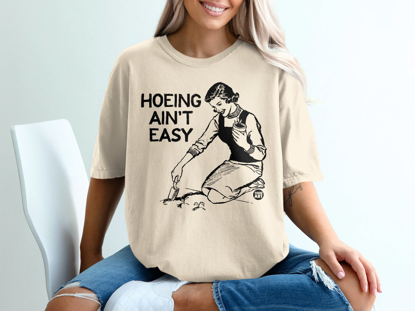 T-shirt with graphic: woman gardening, text "HOEING AIN'T EASY".