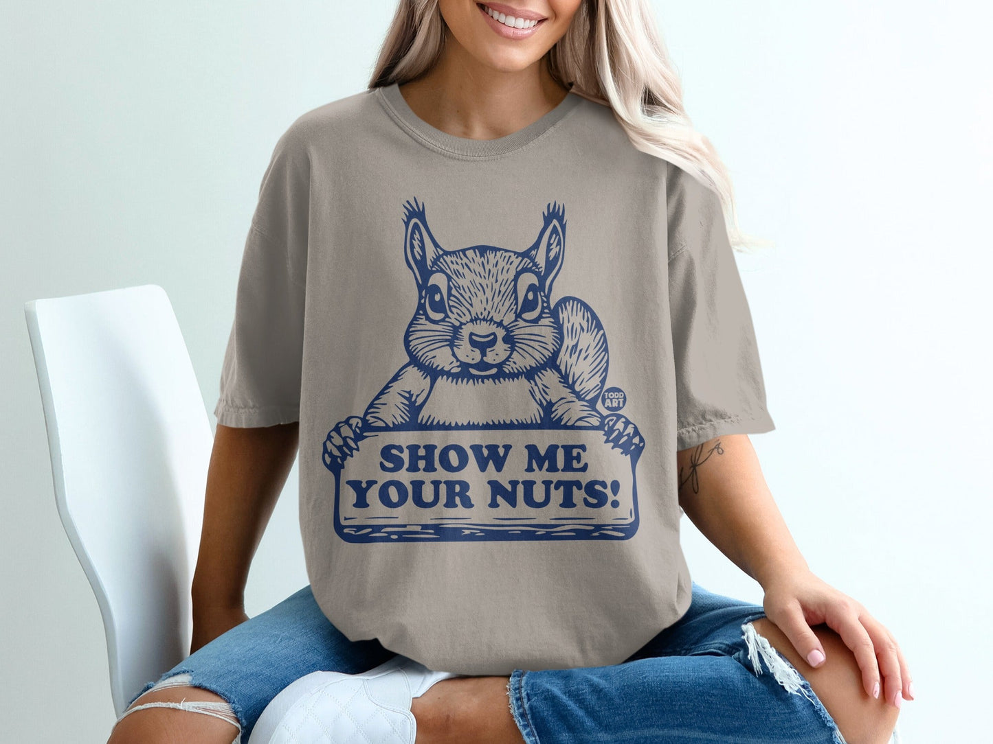T-shirt with a squirrel holding a sign that says "Show Me Your Nuts!"