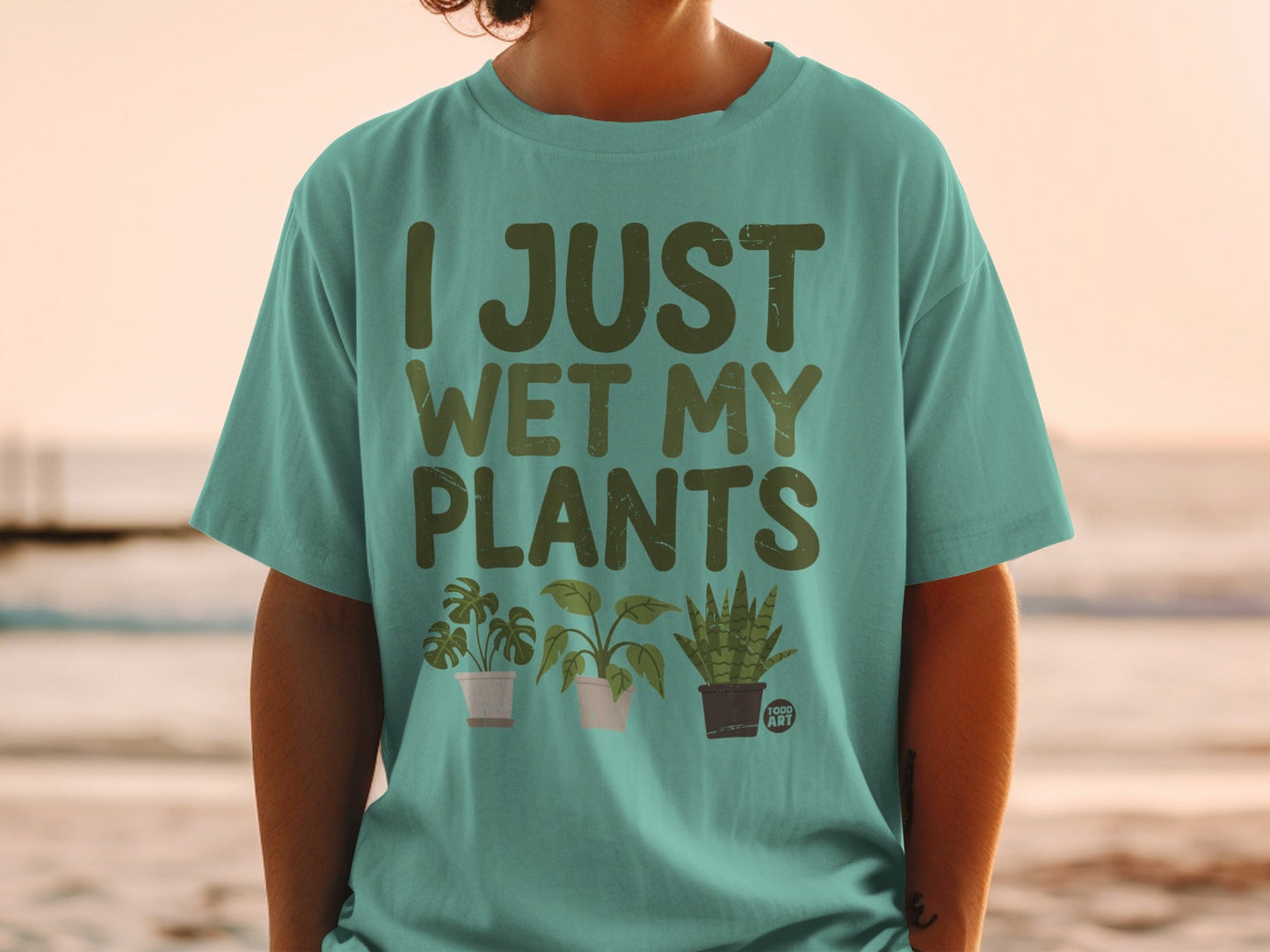 Teal t-shirt with "I JUST WET MY PLANTS" and three illustrated potted plants.