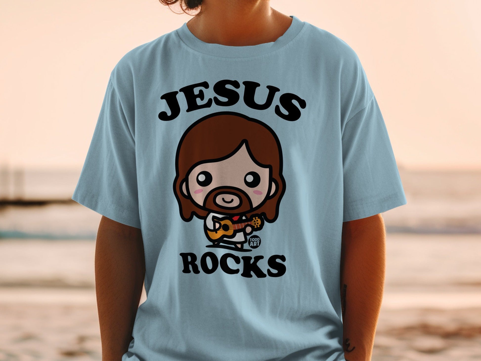Light blue t-shirt featuring a chibi Jesus playing a ukulele.