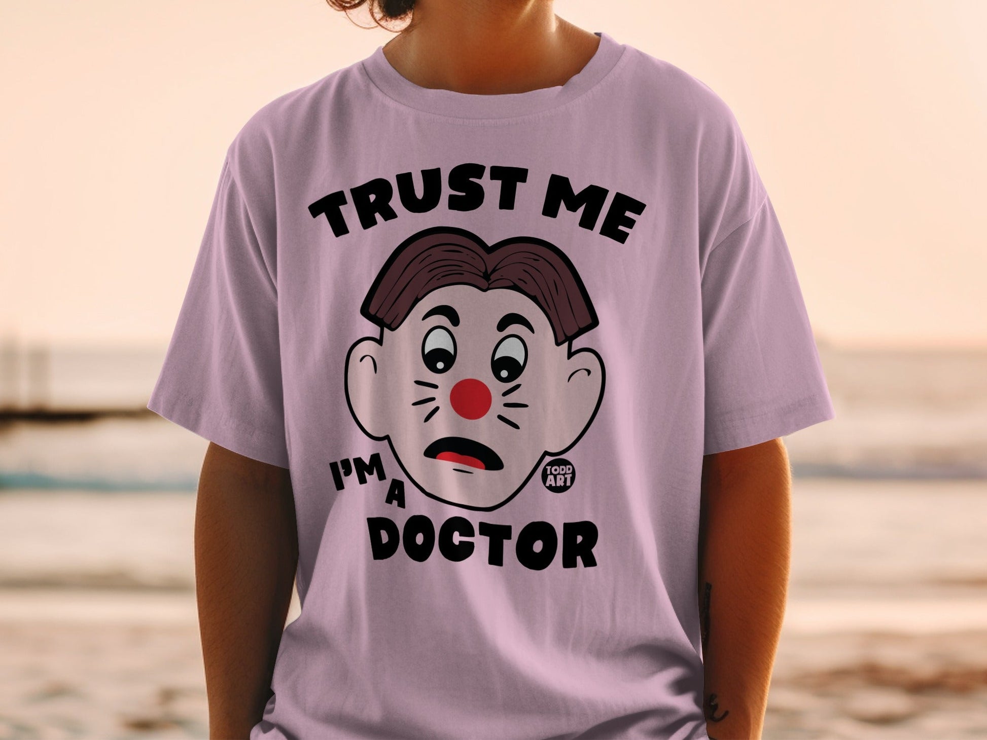 Purple t-shirt with cartoon doctor face and "TRUST ME I'M A DOCTOR" text.