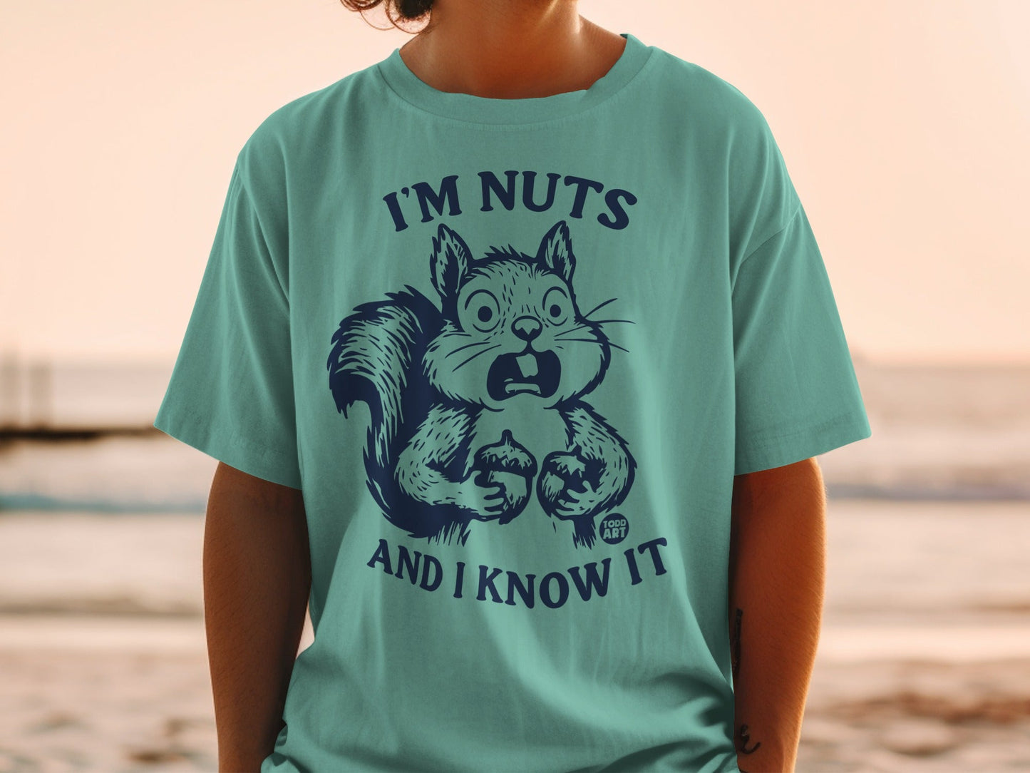Teal t-shirt with a surprised squirrel holding an acorn and the text "I'm nuts and I know it".