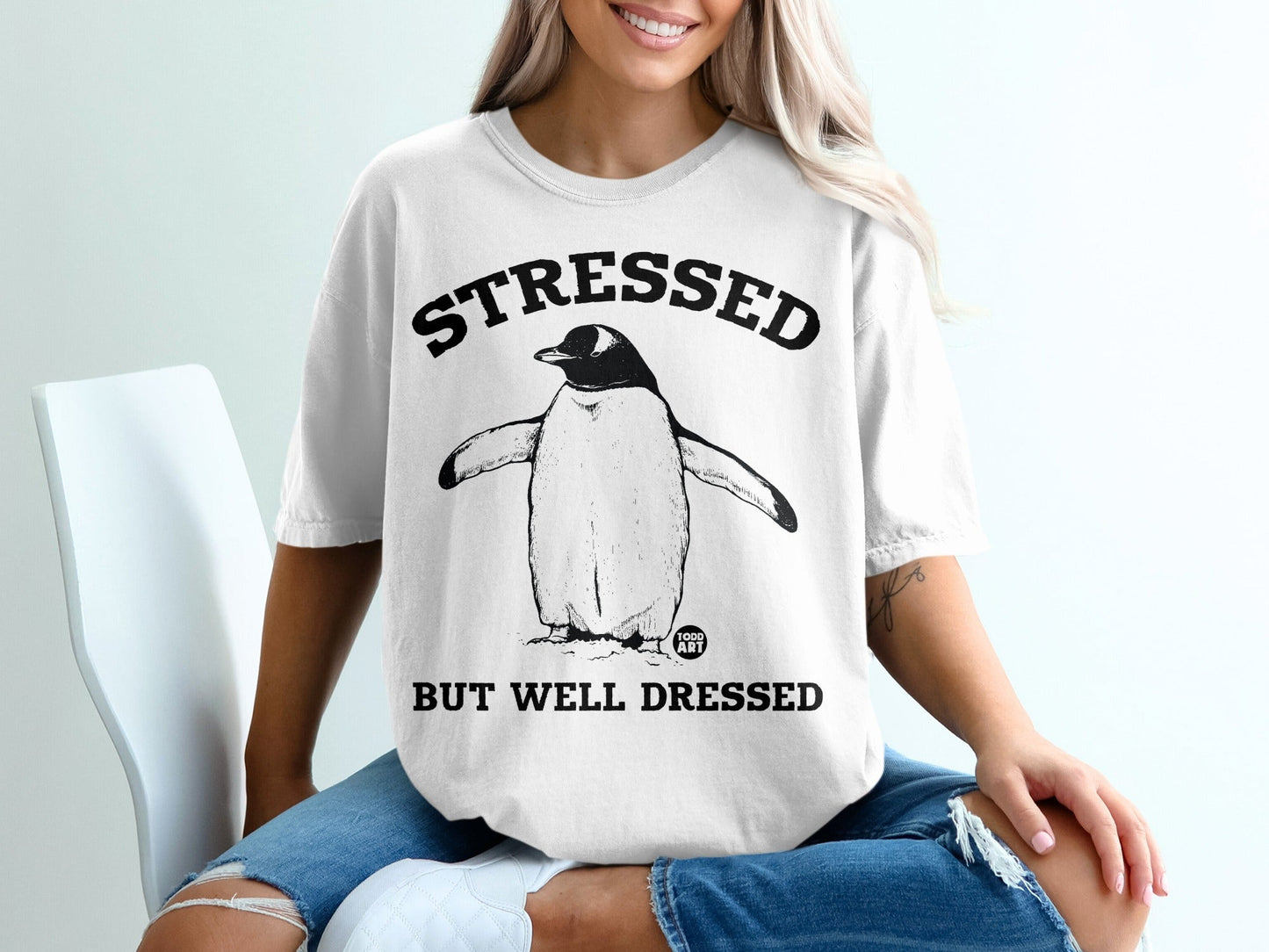 Penguin graphic t-shirt reading "STRESSED BUT WELL DRESSED."