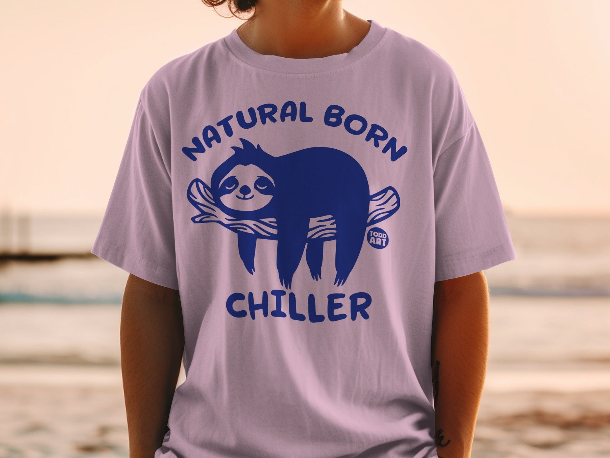 Purple t-shirt with a blue sloth graphic and "Natural Born Chiller" text.