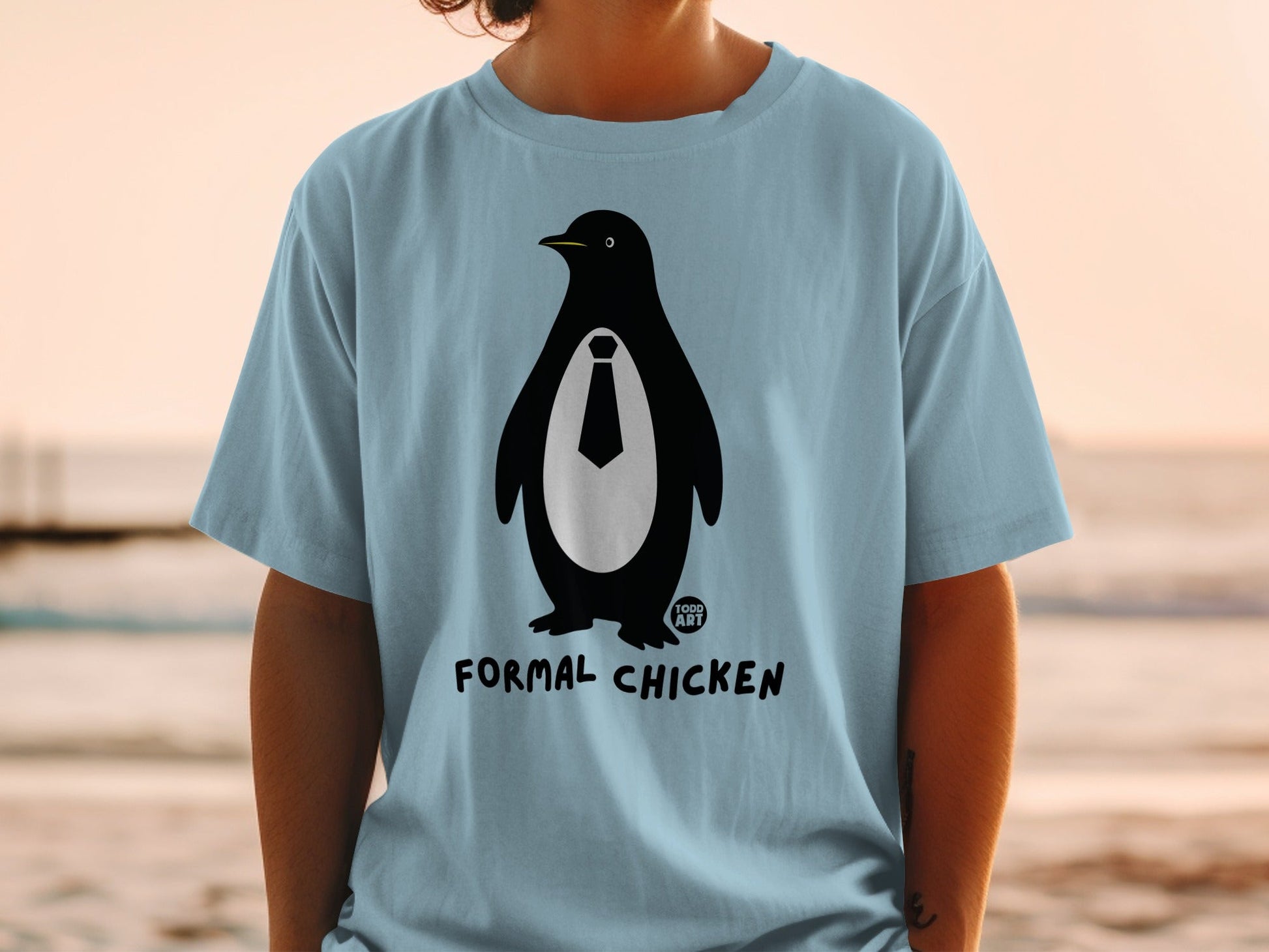 Light blue t-shirt with a penguin wearing a tie and the words "TODD ART FORMAL CHICKEN".
