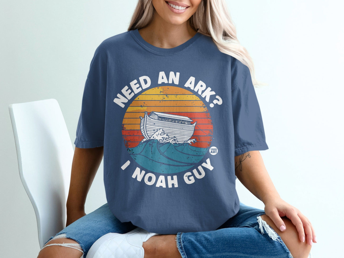 T-shirt with "NEED AN ARK? I NOAH GUY" text and a sunset over waves.