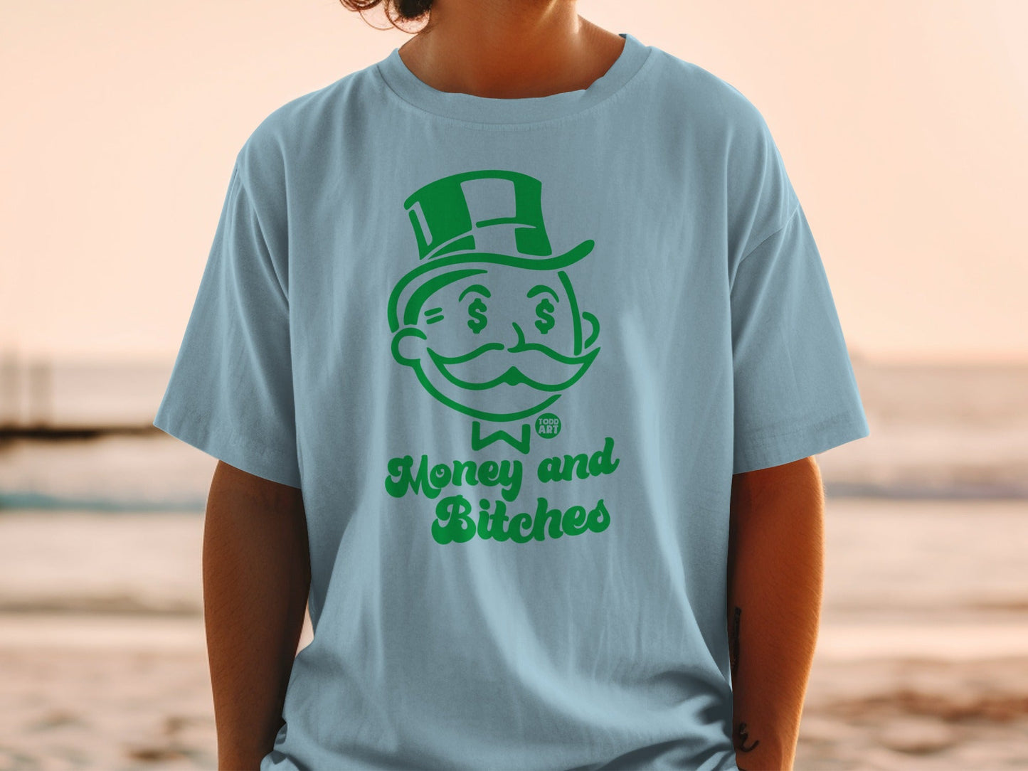 Light blue t-shirt featuring a green Monopoly Man graphic with "Money and Bitches" text.