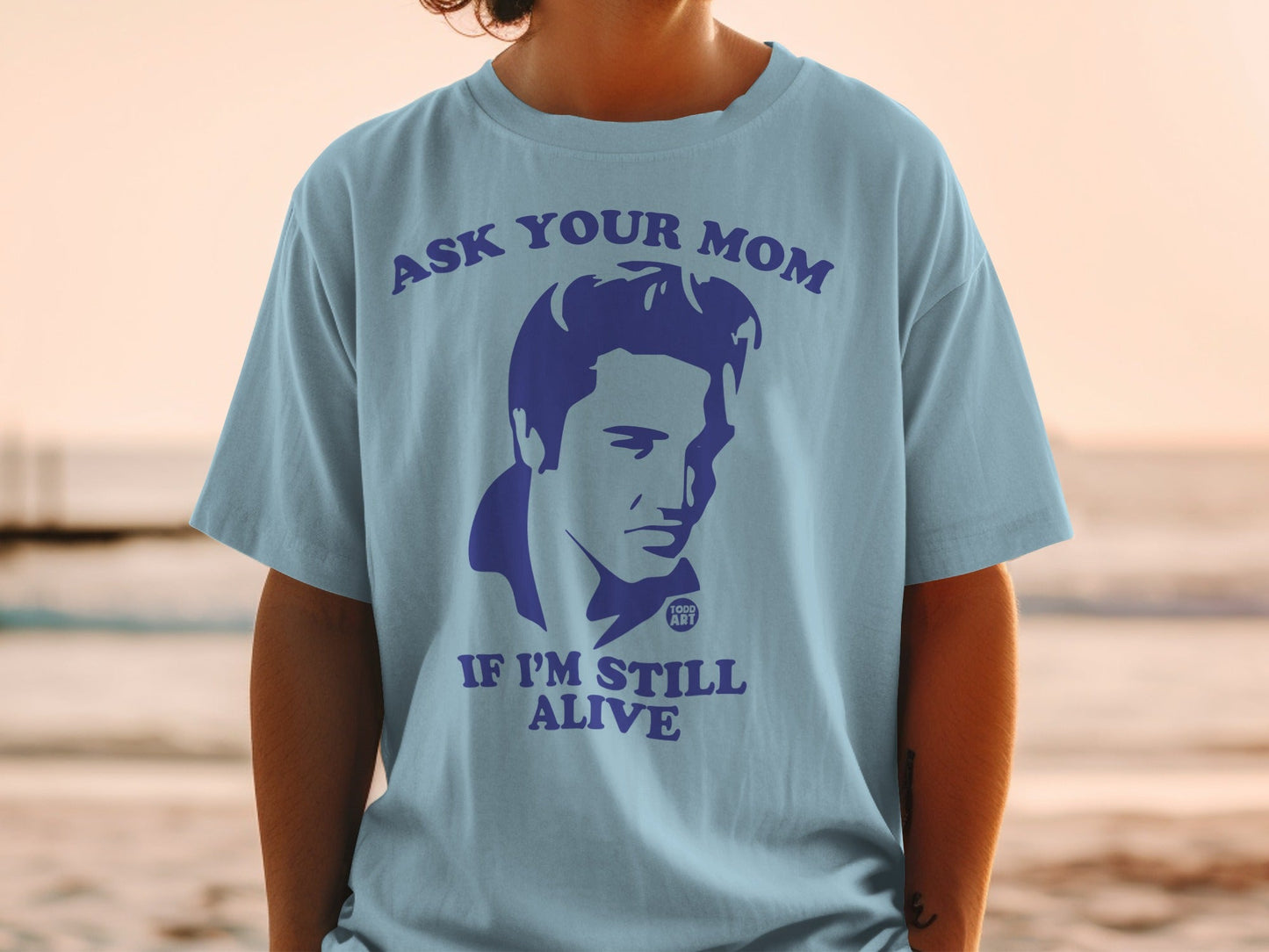 Light blue t-shirt with an Elvis graphic and "Ask Your Mom If I'm Still Alive" text.