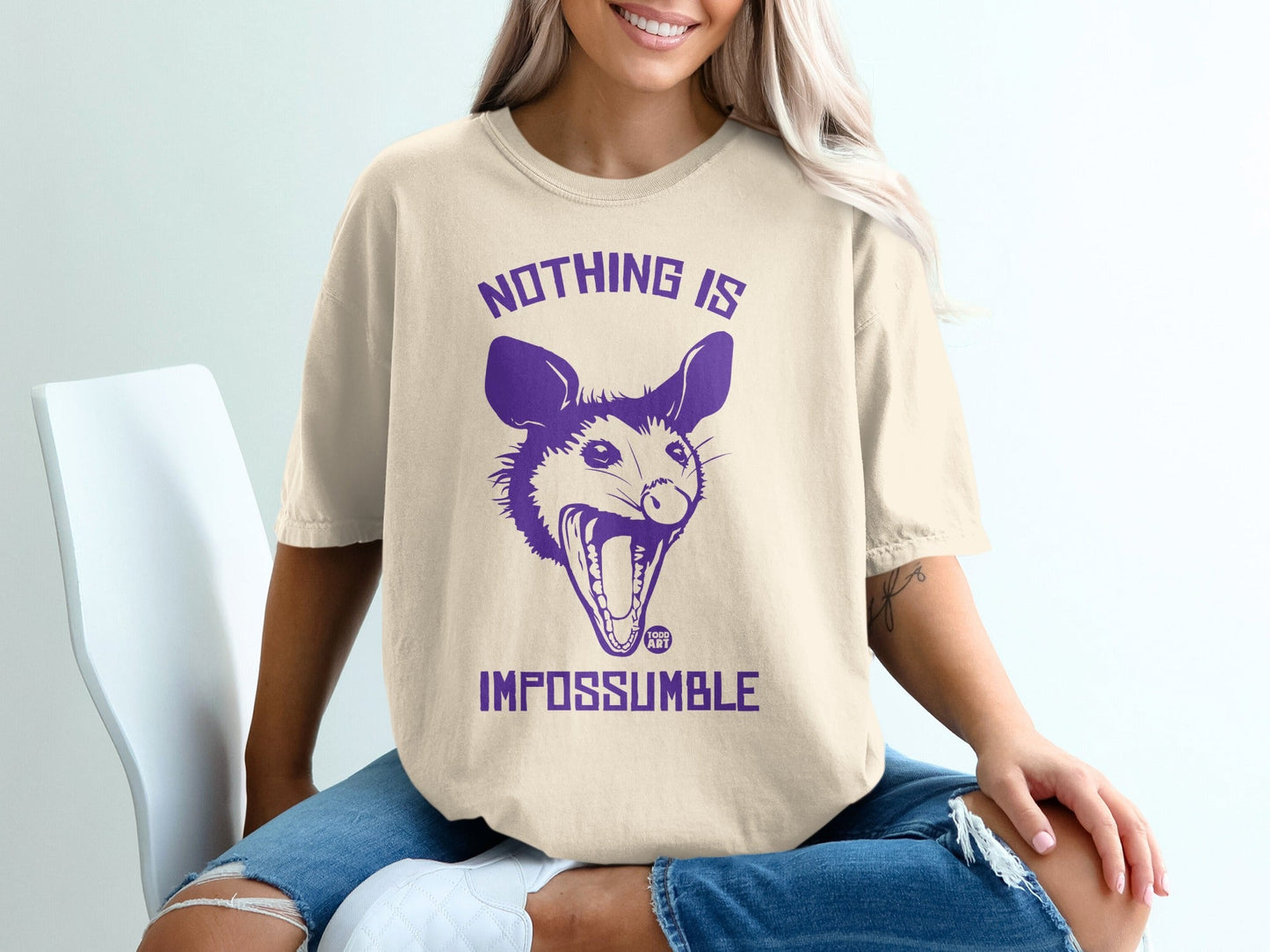 Beige t-shirt with purple text "NOTHING IS IMPOSSUMBLE" and a possum graphic.